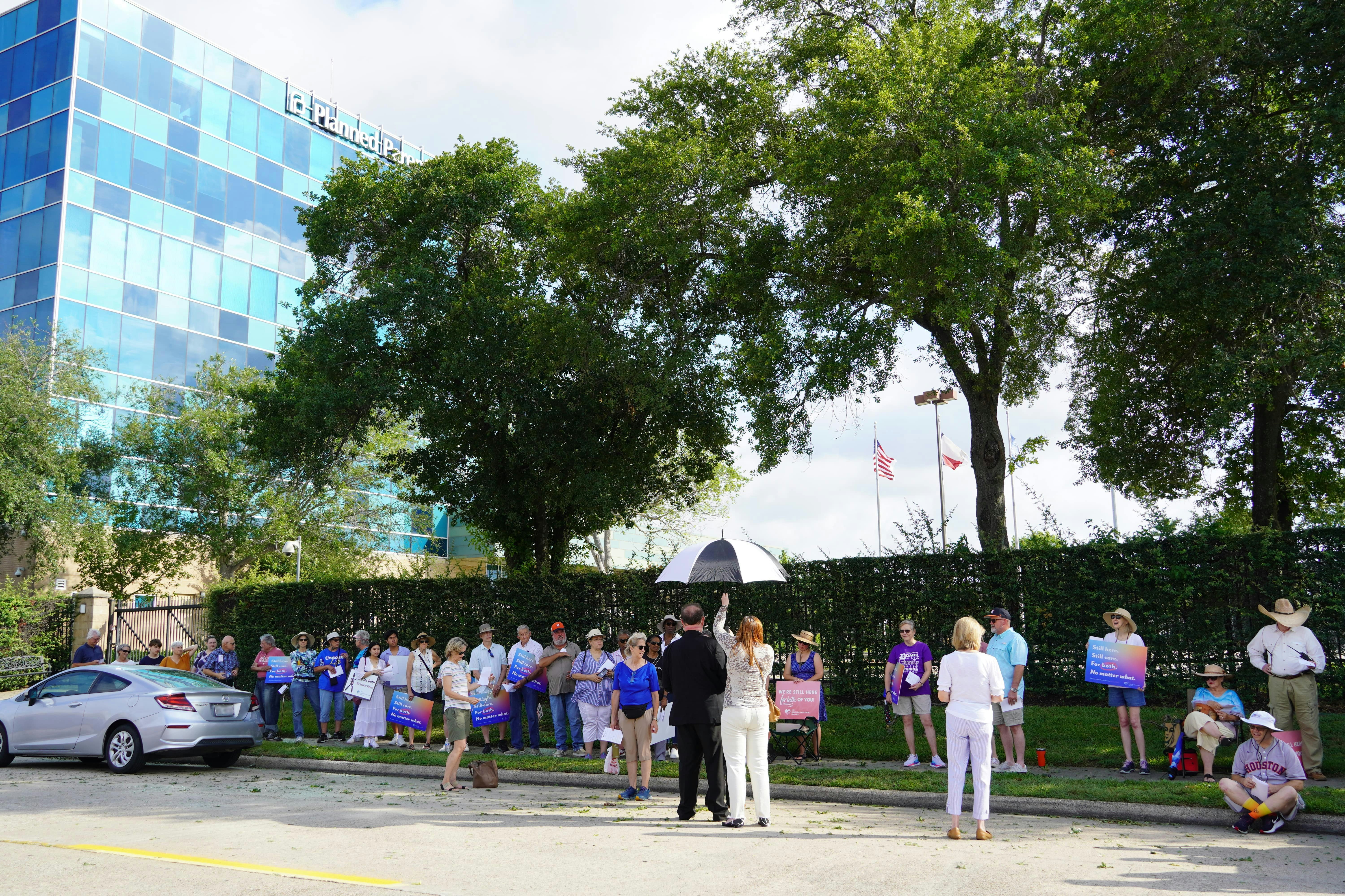 La gente se reúne frente a un edificio moderno con árboles.