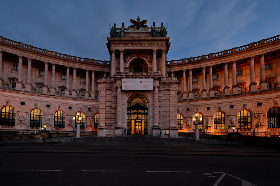 Grand building with central dome and columns, illuminated by warm light from windows