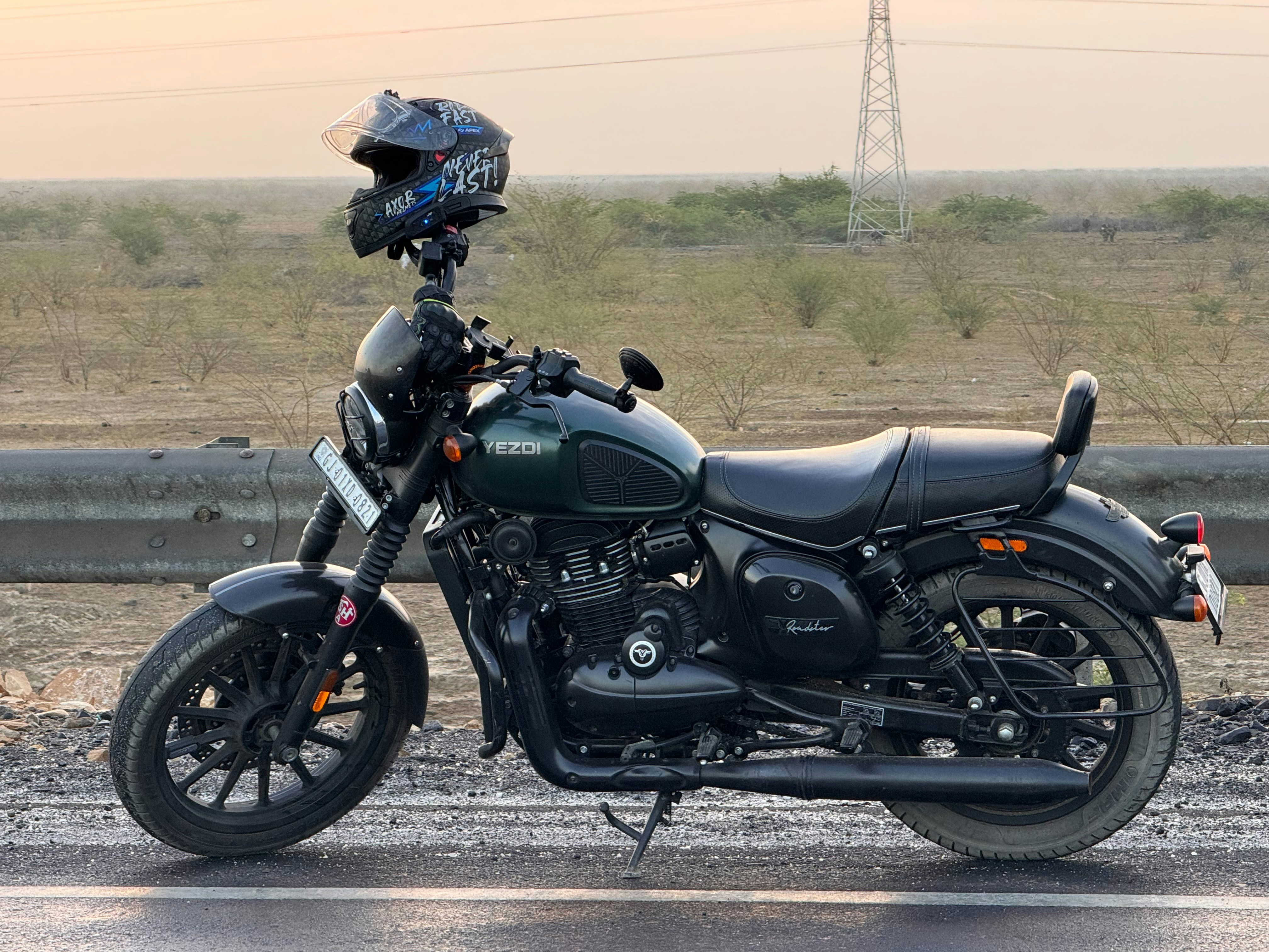 A dark green motorcycle parked on a roadside.