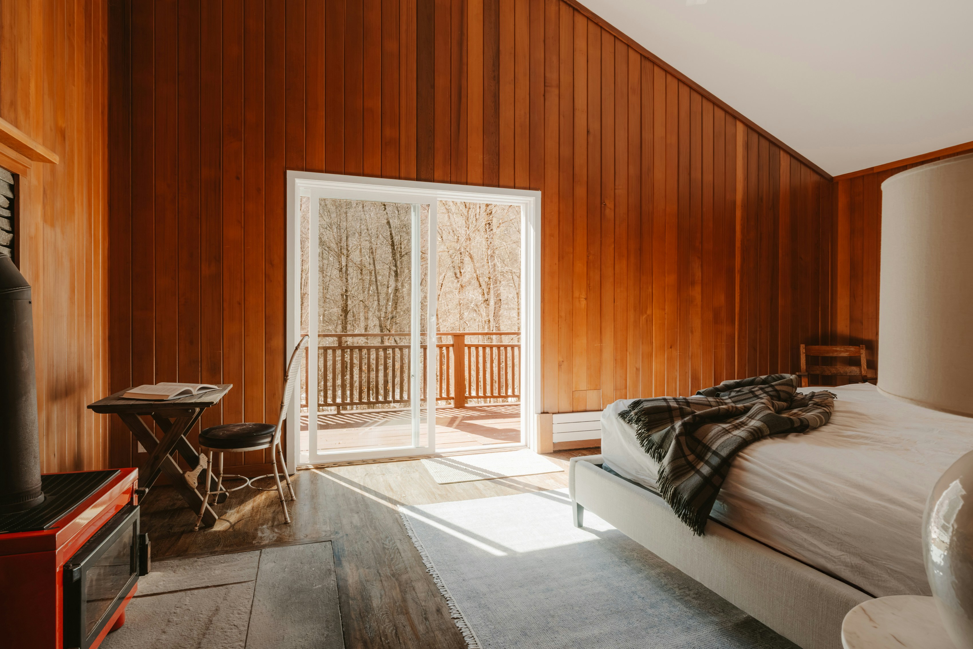 Cozy bedroom with wood paneled walls and a view.