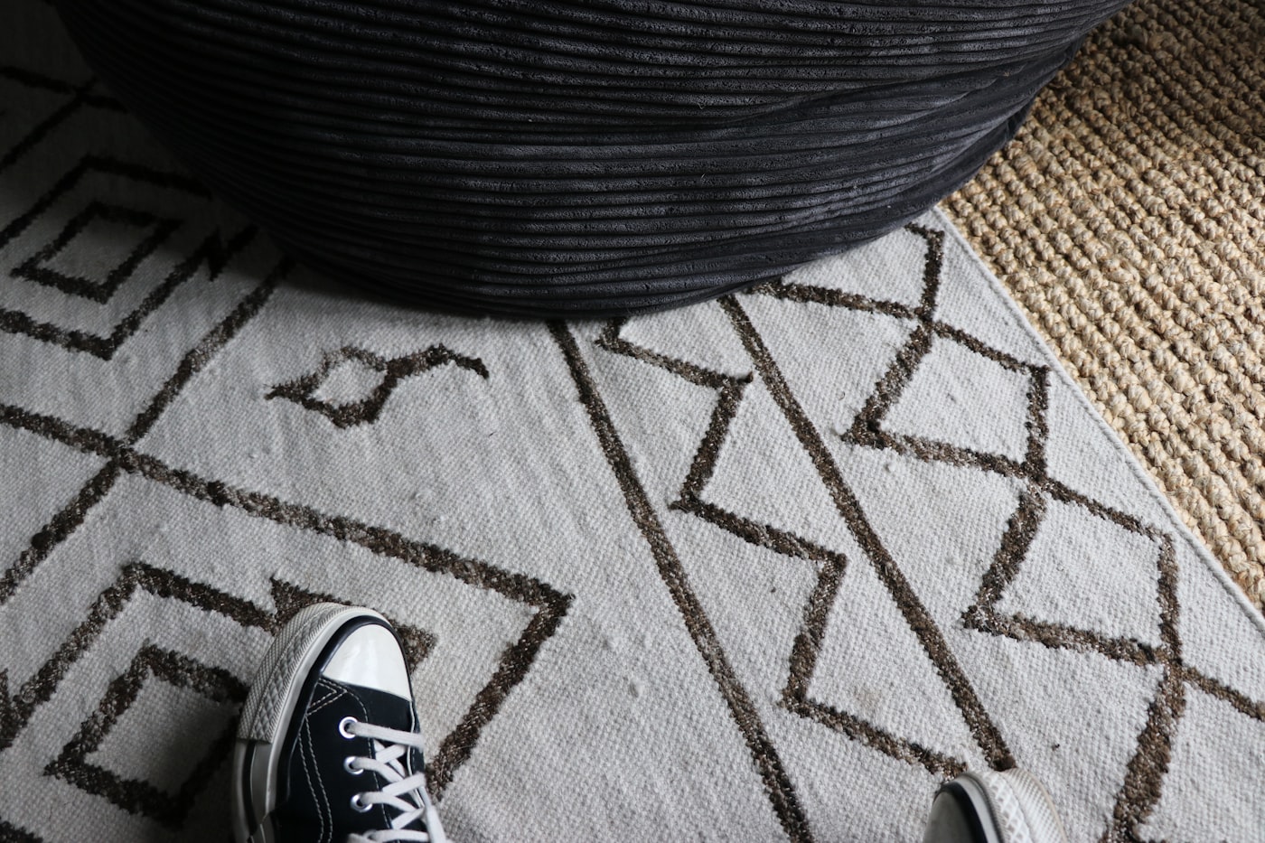 Layered Berber-style geometric rug on top of a natural jute rug in a boho apartment, classic budget boho floor combo
