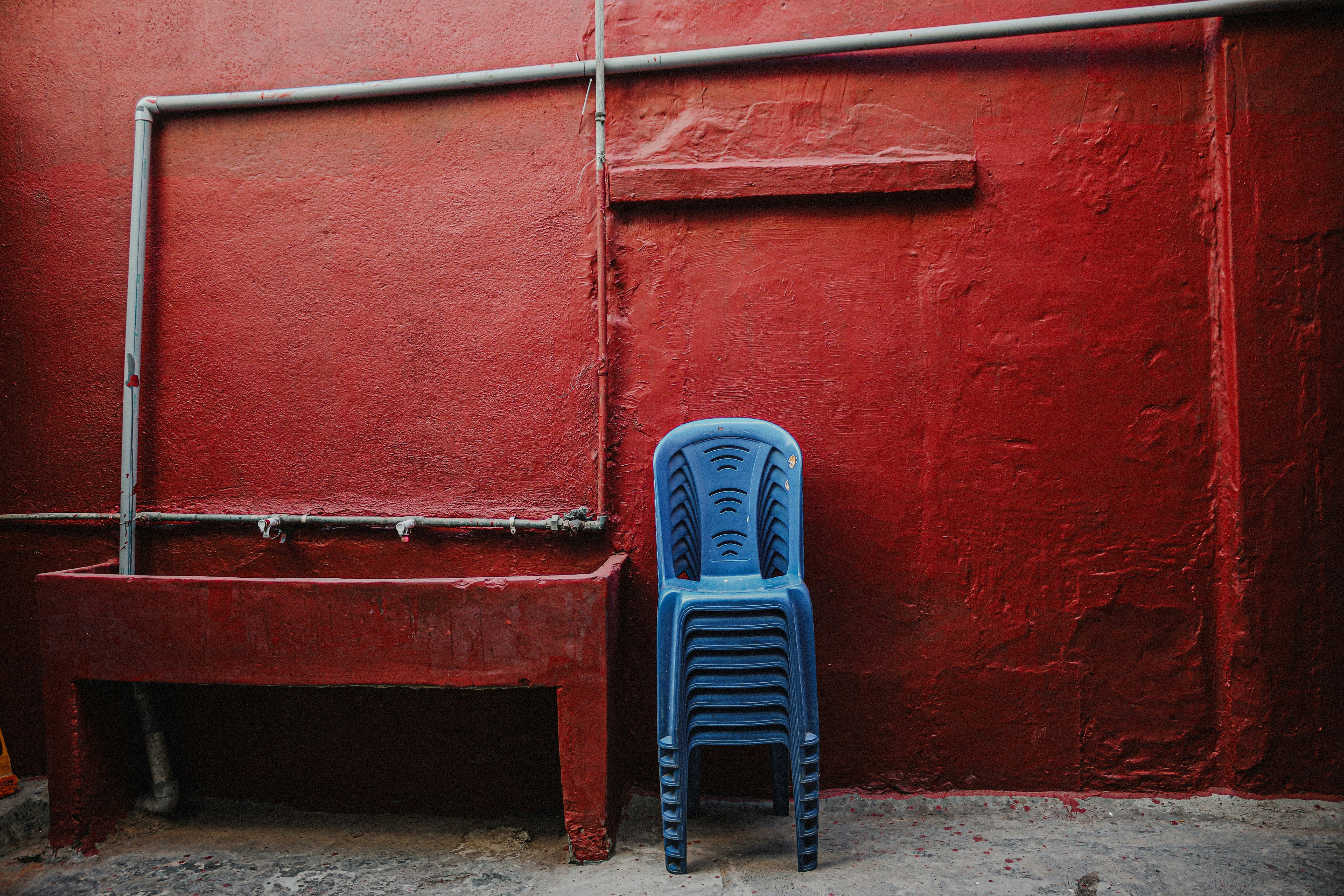Stacked blue chairs against a red wall