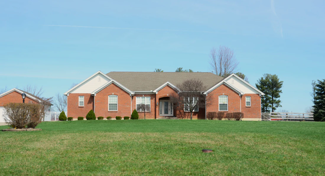 Brick ranch house on a wide green lawn under blue sky