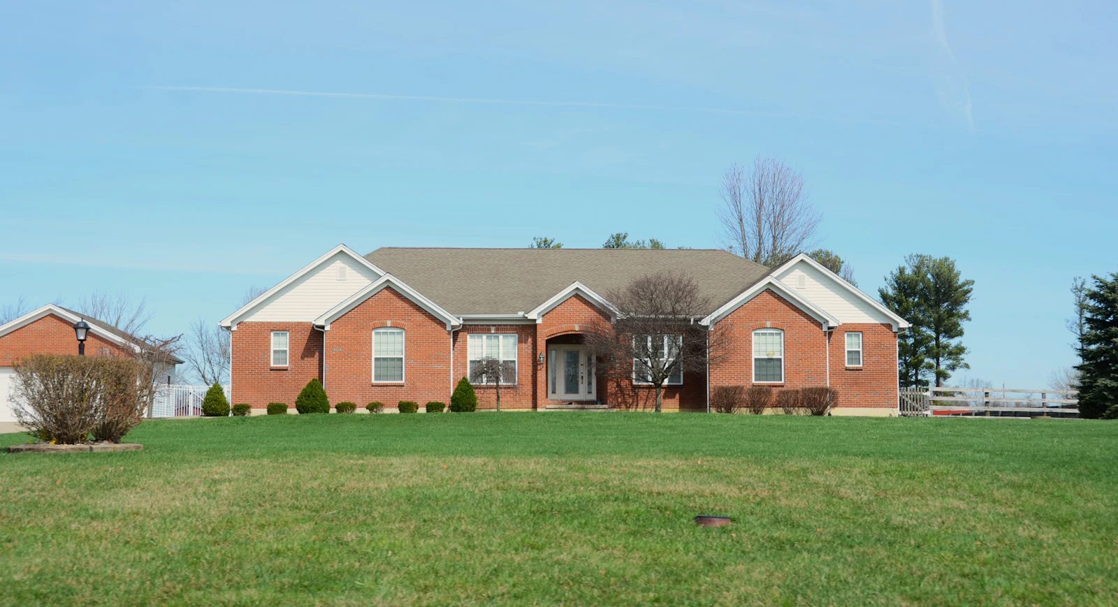 A large brick home with a manicured lawn.