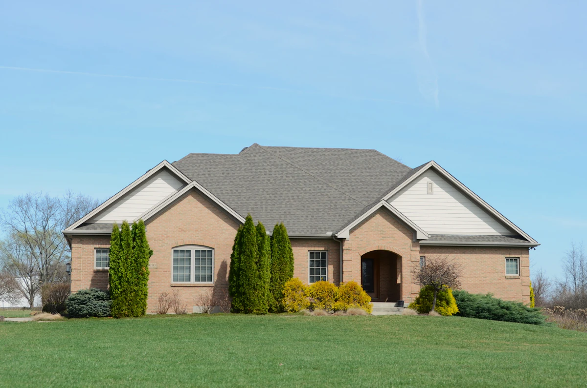 A freshly landscaped suburban front yard with new sod, mulched beds, and stone edging in mid-morning light