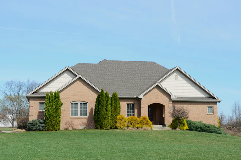 Tan brick ranch house set back on a wide lawn