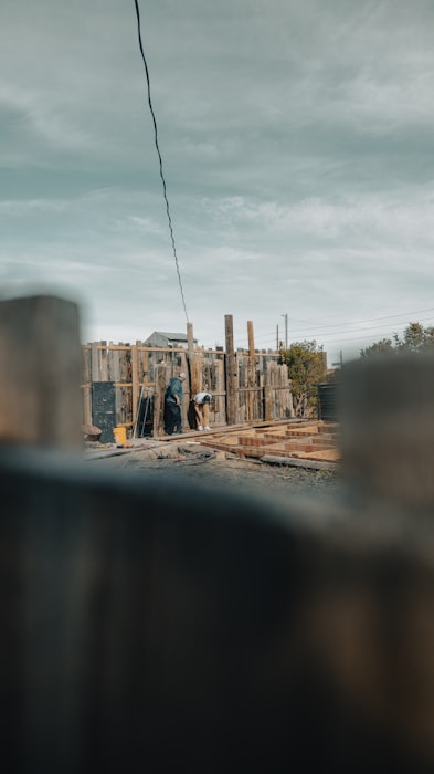 Two contractors framing a wooden structure on a jobsite while comparing the best Joist alternatives for 2026 contractor estimating apps