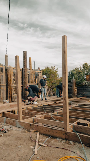 Construction workers build a wooden deck outdoors.
