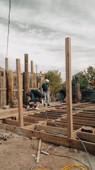 Construction workers build a wooden deck outdoors.