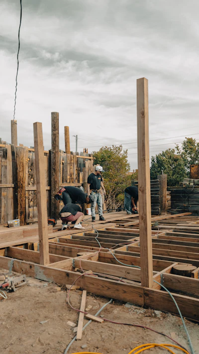 Construction workers build a wooden deck outdoors.