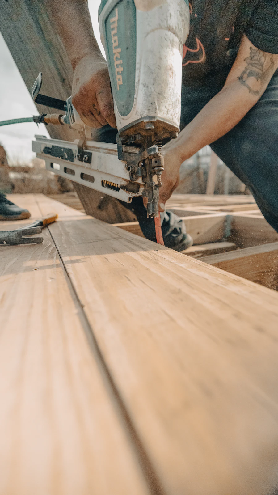 Worker fixing wooden planks with a nail gun