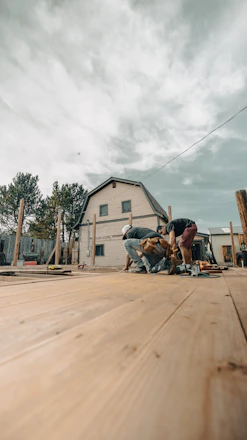 Construction workers building a wooden deck near a house.