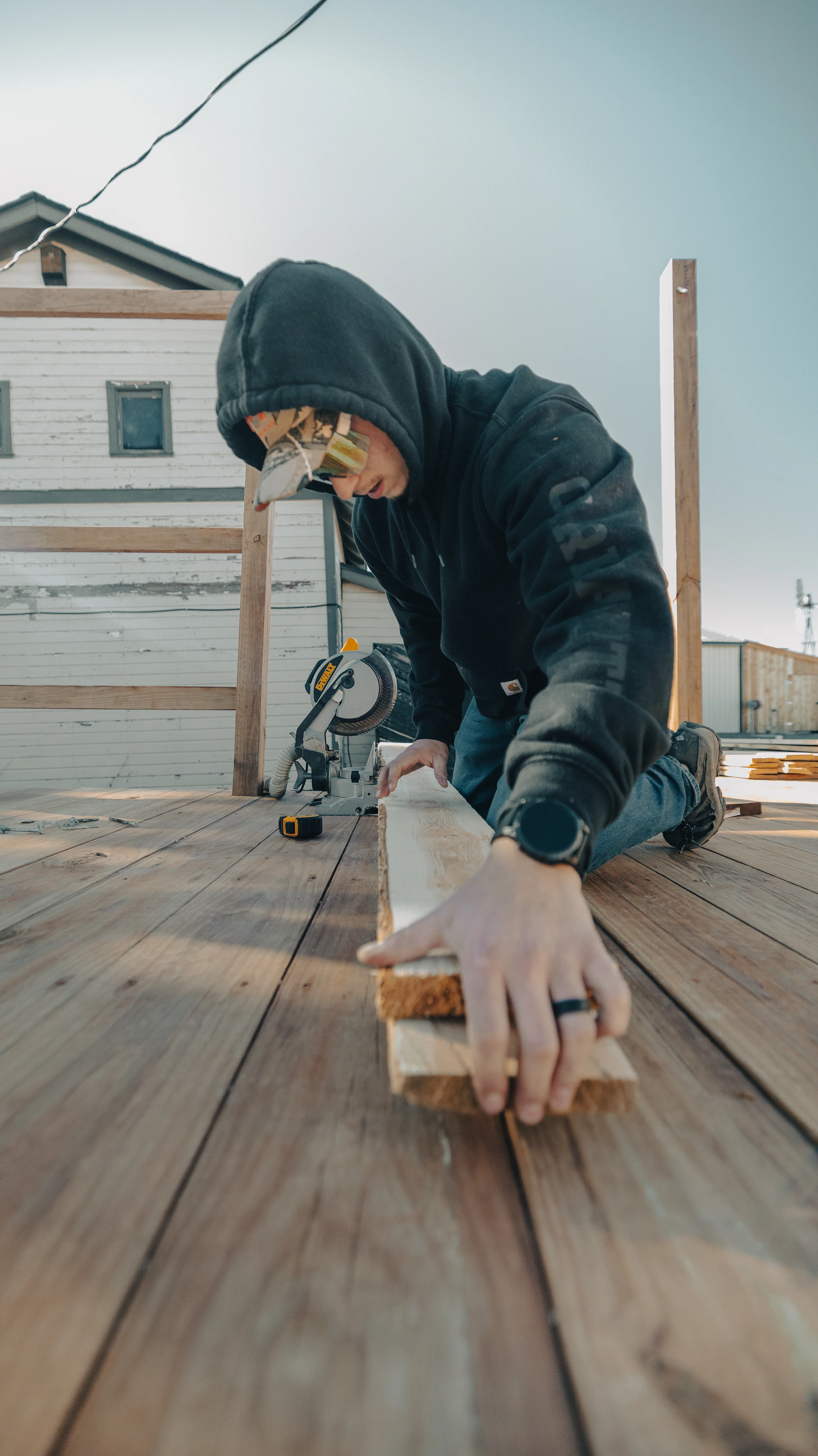 A person wearing safety glasses cuts wood with a saw.