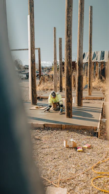 Construction worker smoothing wet concrete slab with tools.