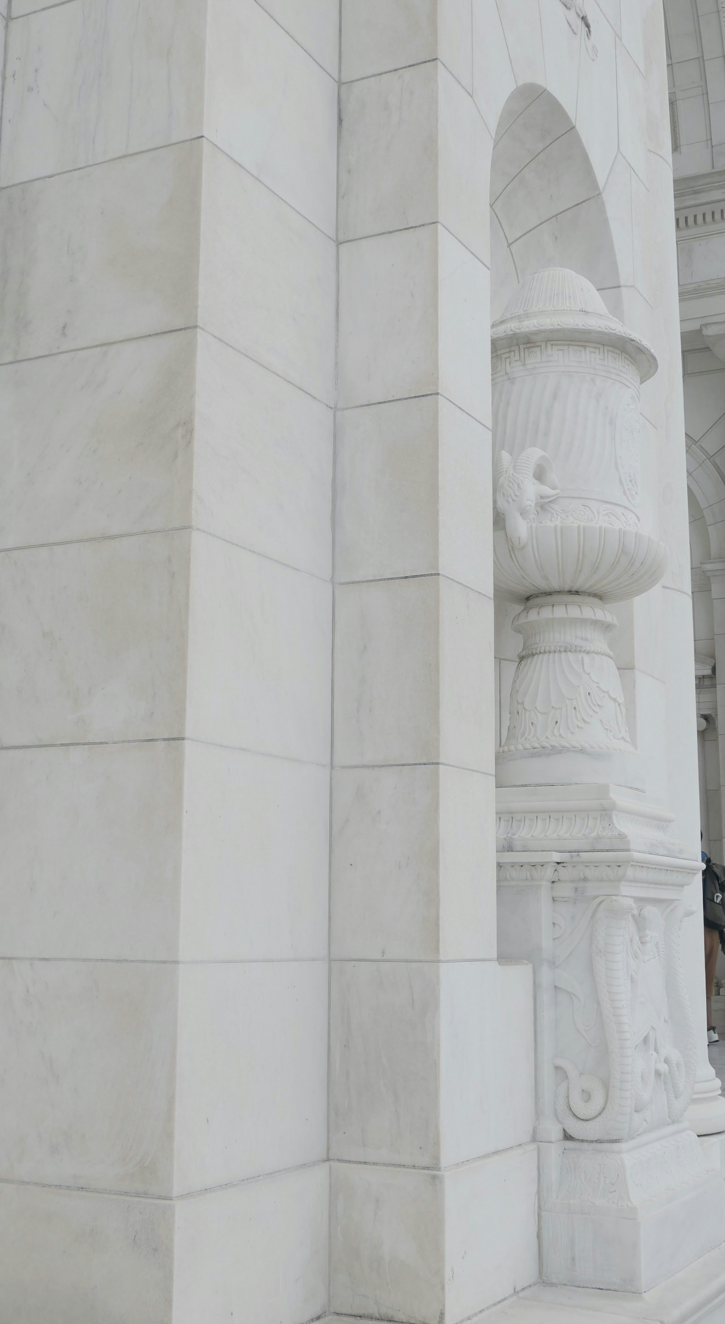 建築的な細部が施された台座の上に置かれた白い大理石の壺。