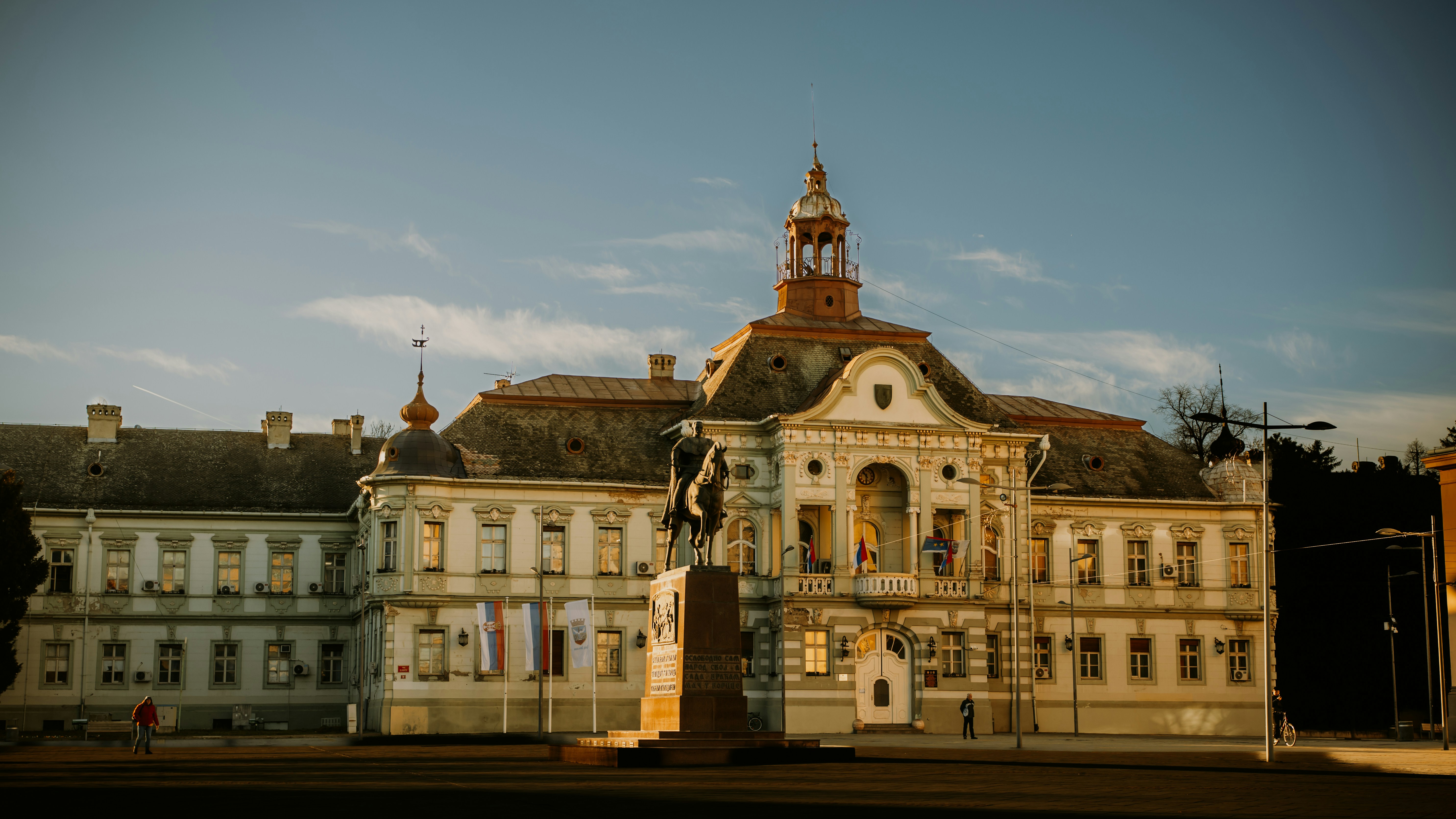 Historic building with a statue in front at sunset