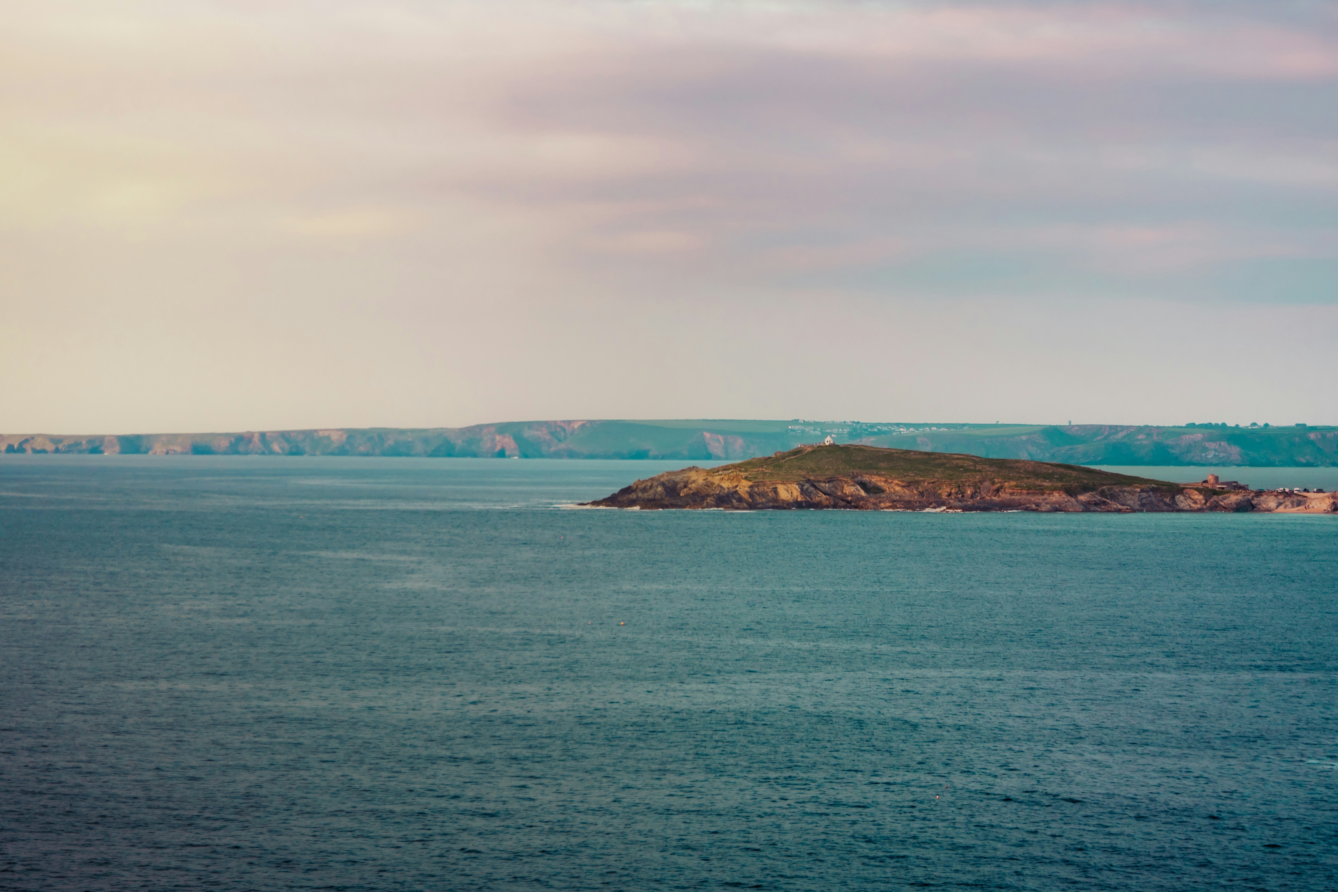 A small island sits in the vast blue ocean.