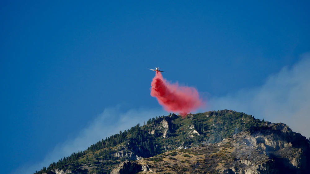 Air tanker releasing retardant along a forested ridgeline