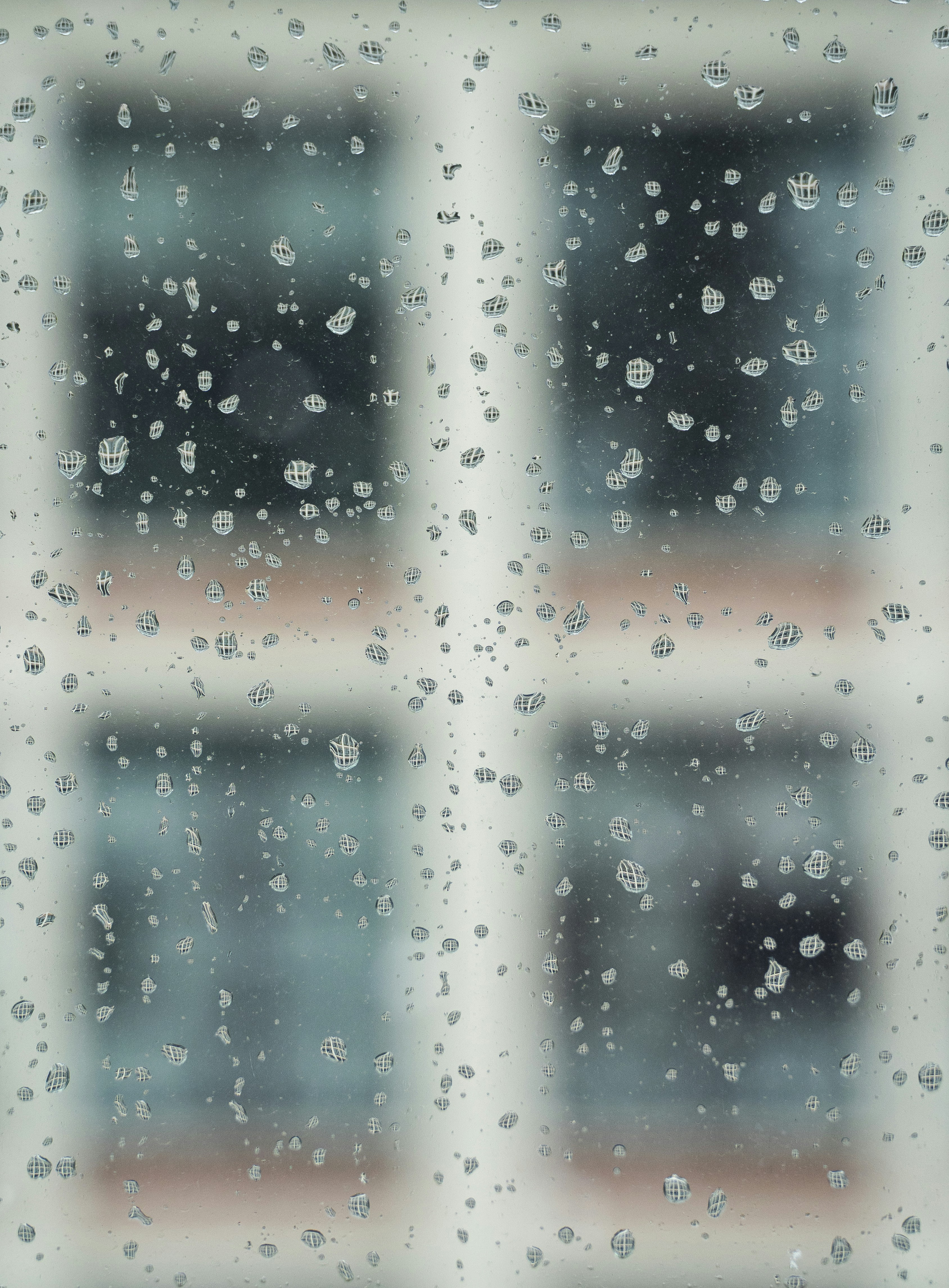 Raindrops on a window pane with blurred background
