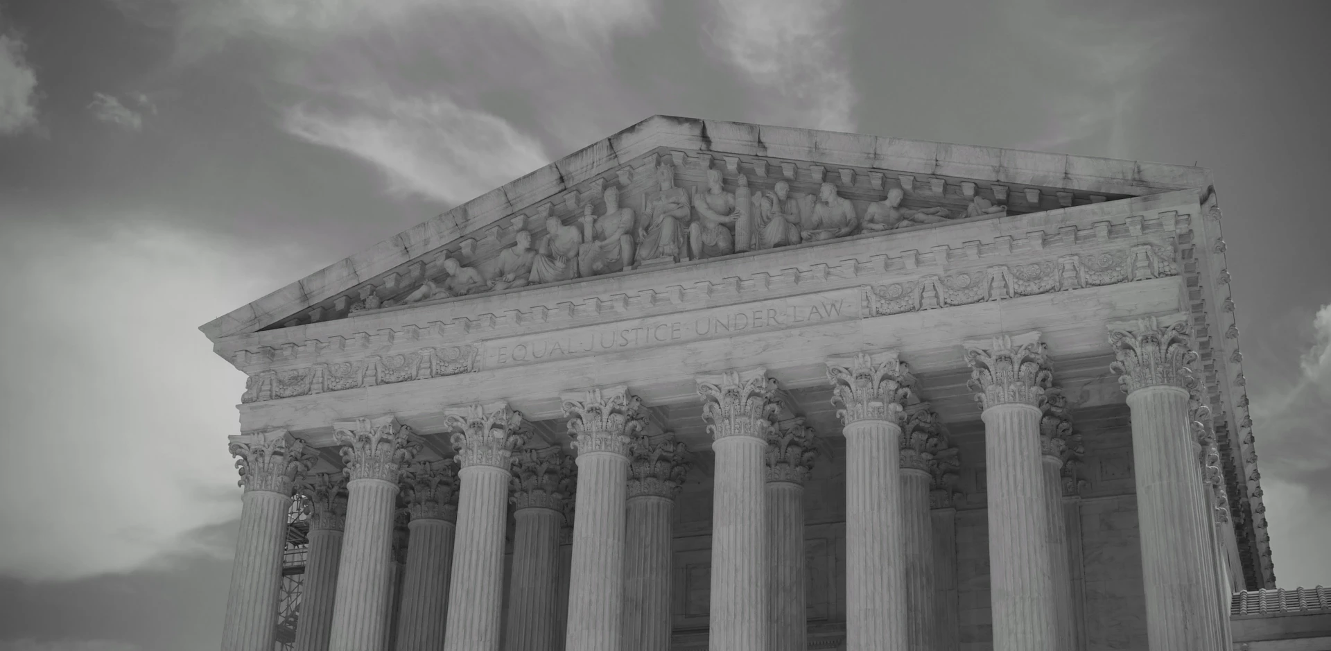 Grand neoclassical building with columns against cloudy sky.