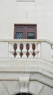A wooden door with decorative windows above a stone balcony.
