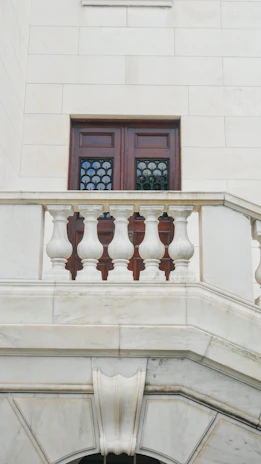 A wooden door with decorative windows above a stone balcony.