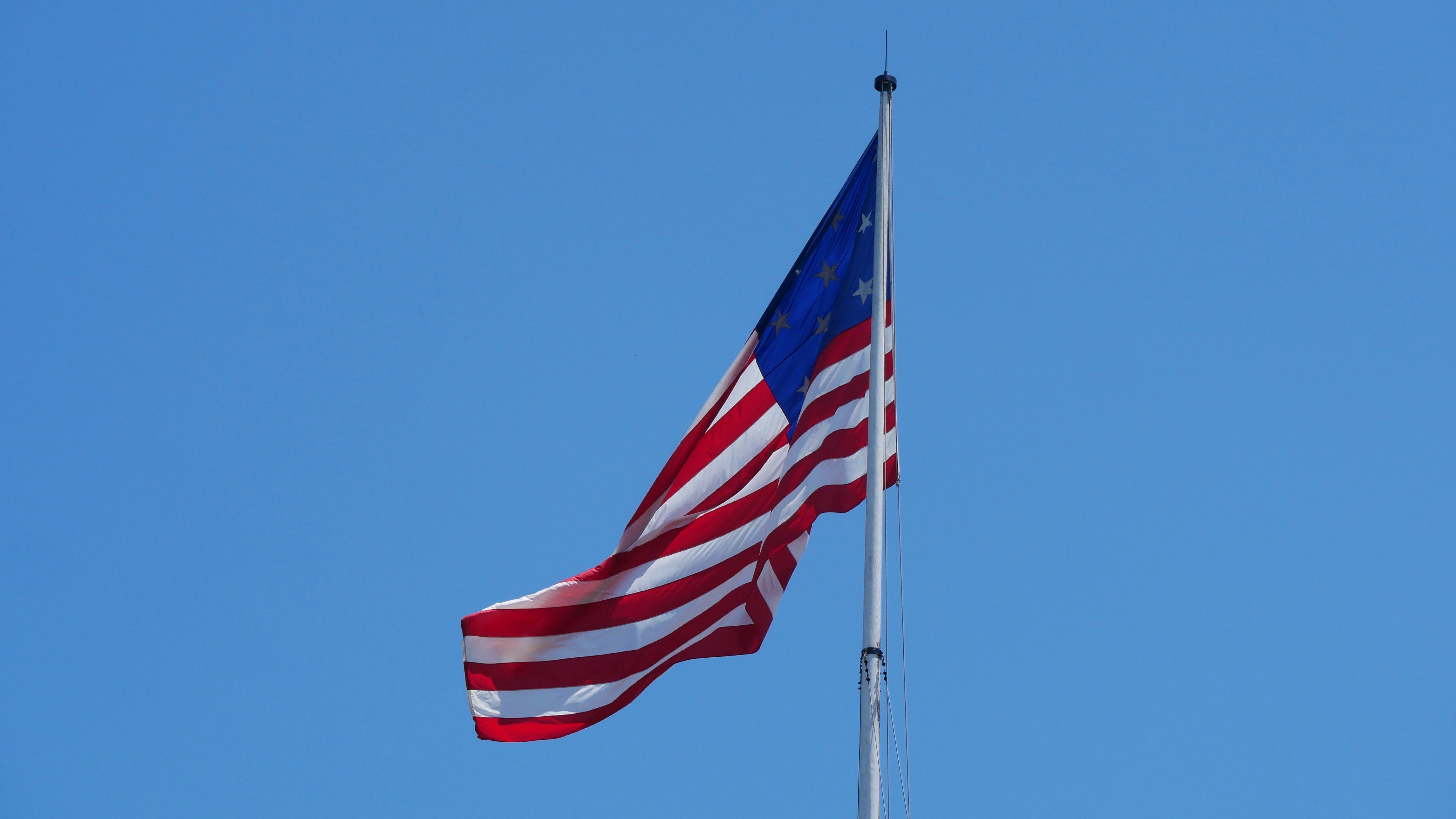 American flag waving against a clear blue sky.
