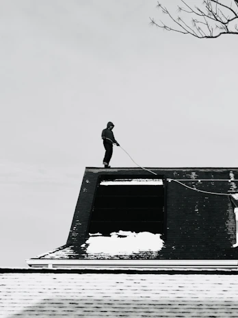 Person on a snowy rooftop with a rope