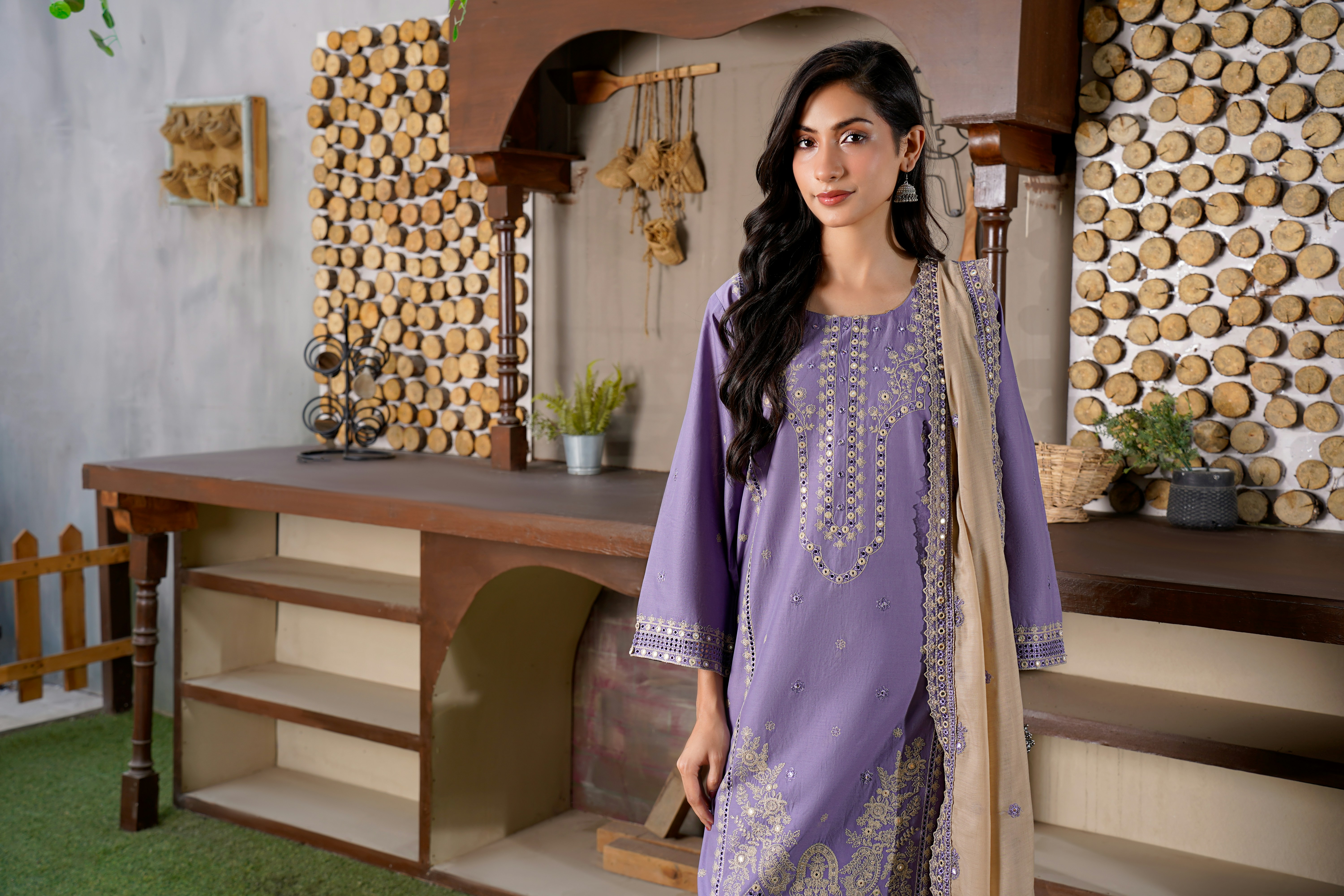 Une femme en tenue violette brodée se tient à l’intérieur.