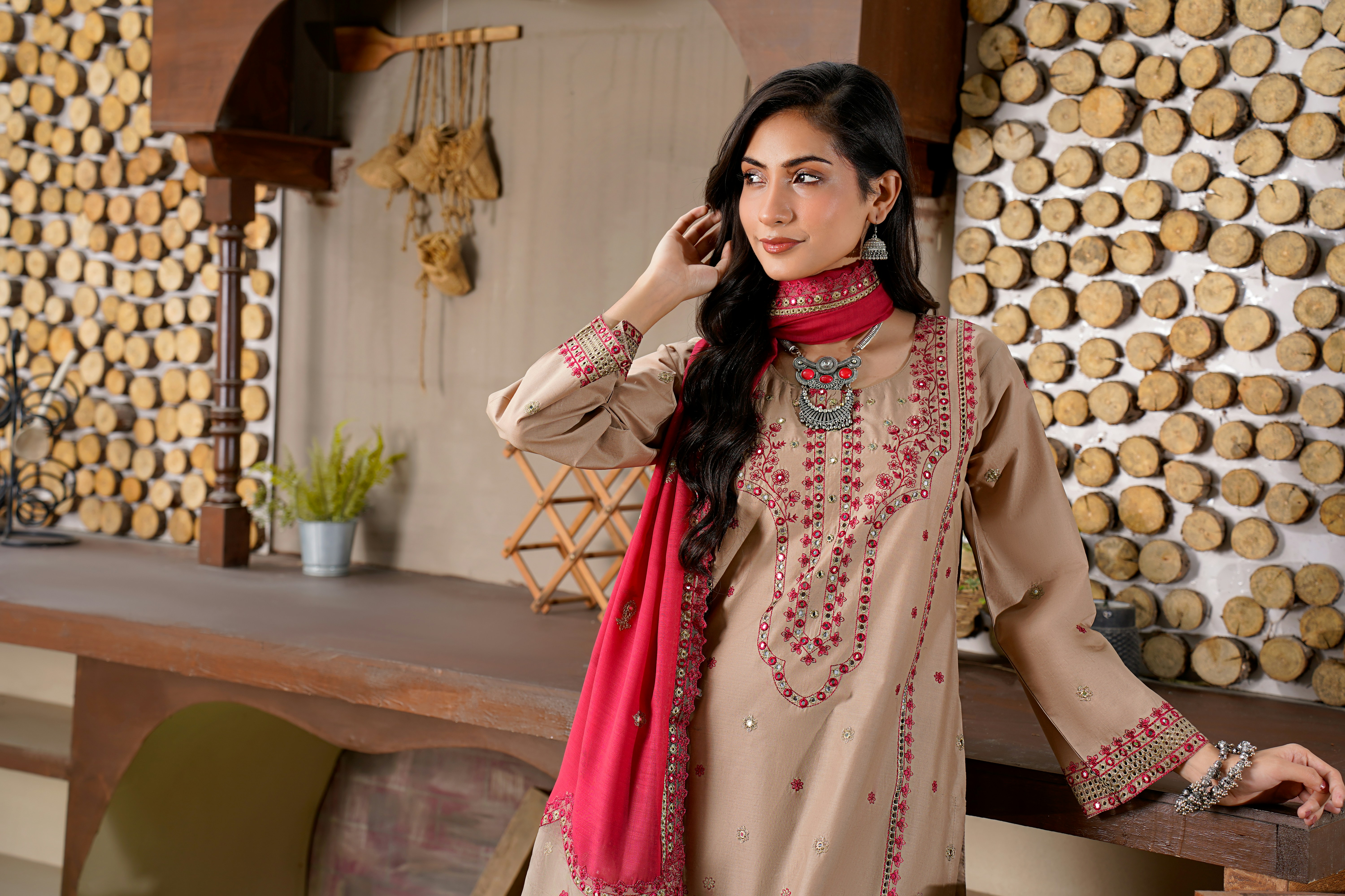 A woman in a beige dress with red scarf.