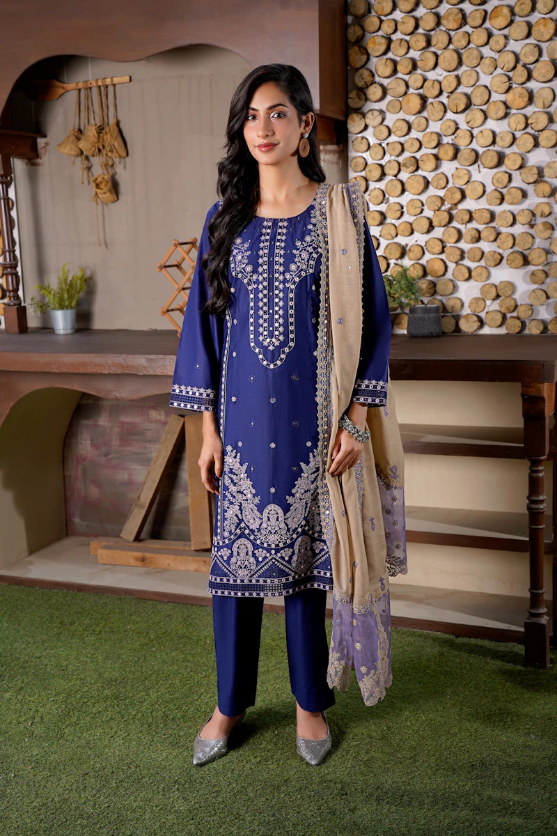 Woman in a blue embroidered outfit with a beige scarf