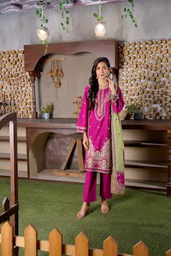 A woman in a pink embroidered outfit stands outdoors.