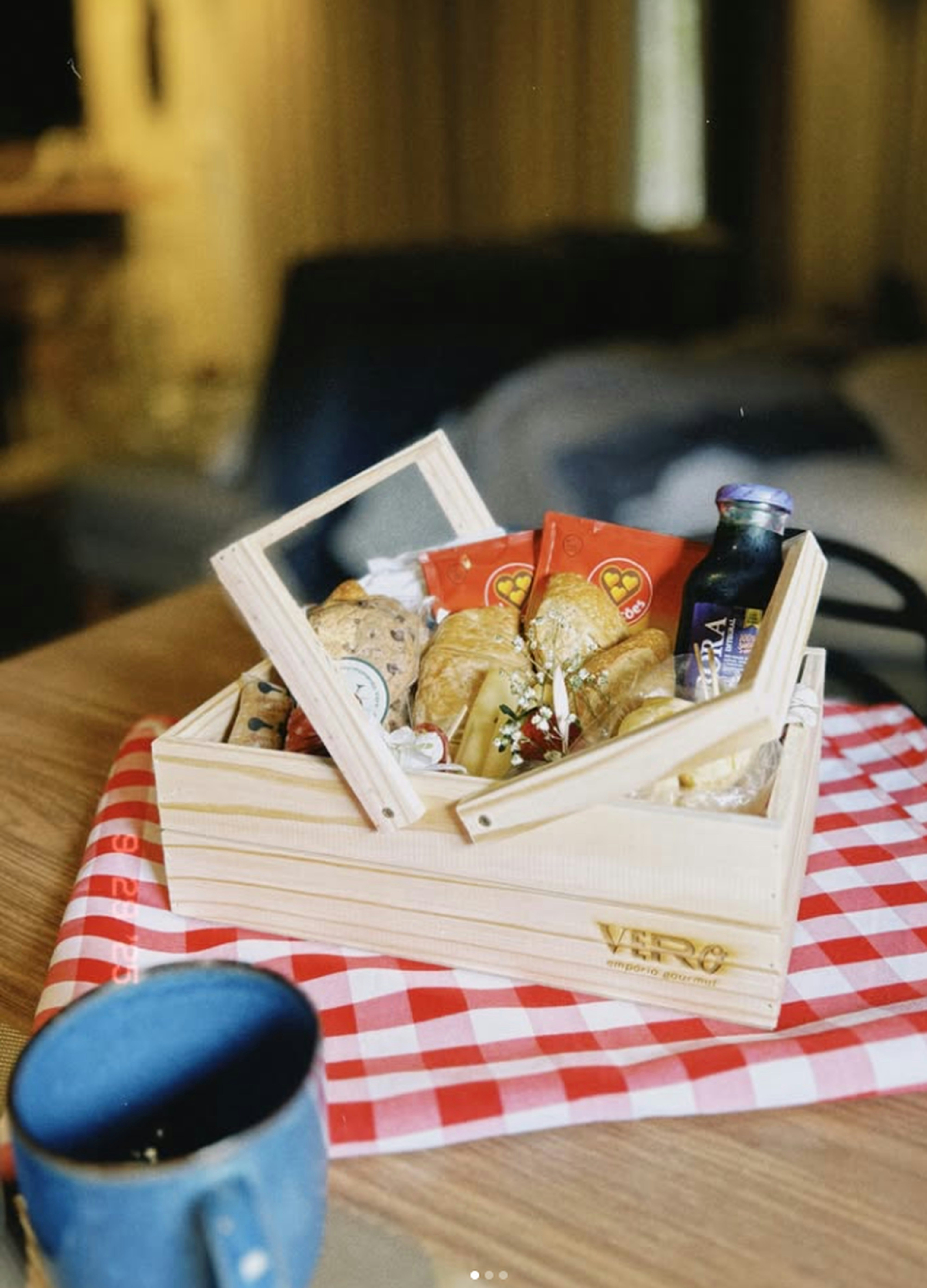 A wooden basket filled with pastries and drinks.