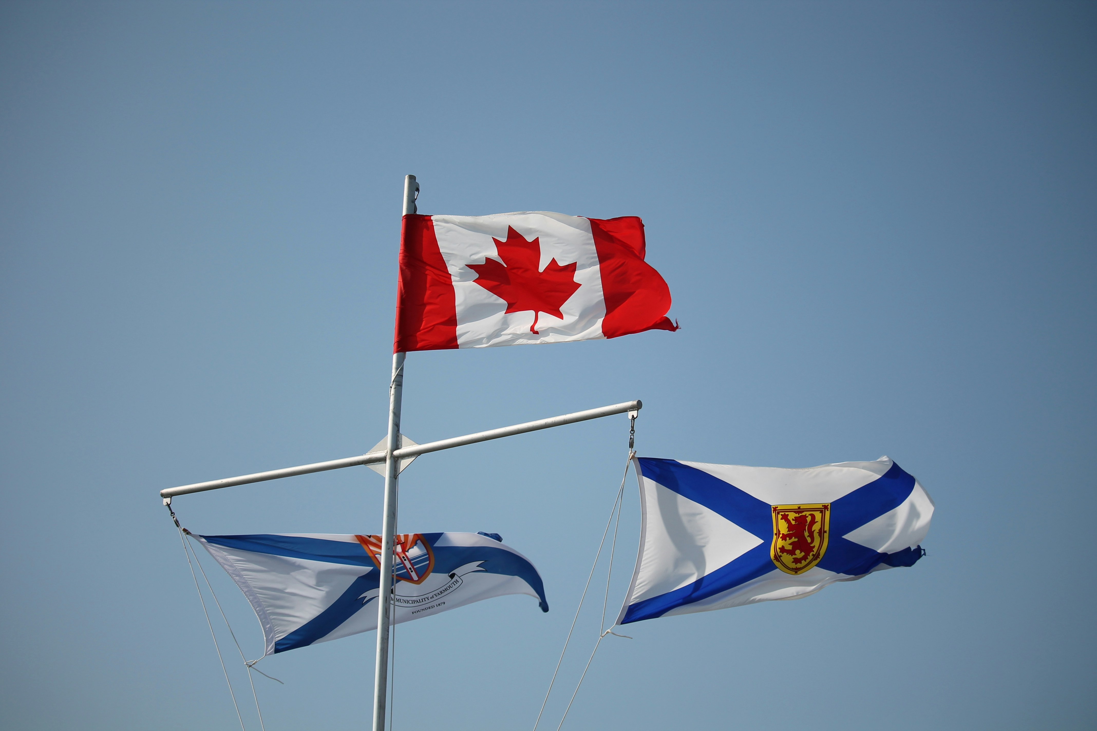 Canadian and nova scotian flags against a blue sky
