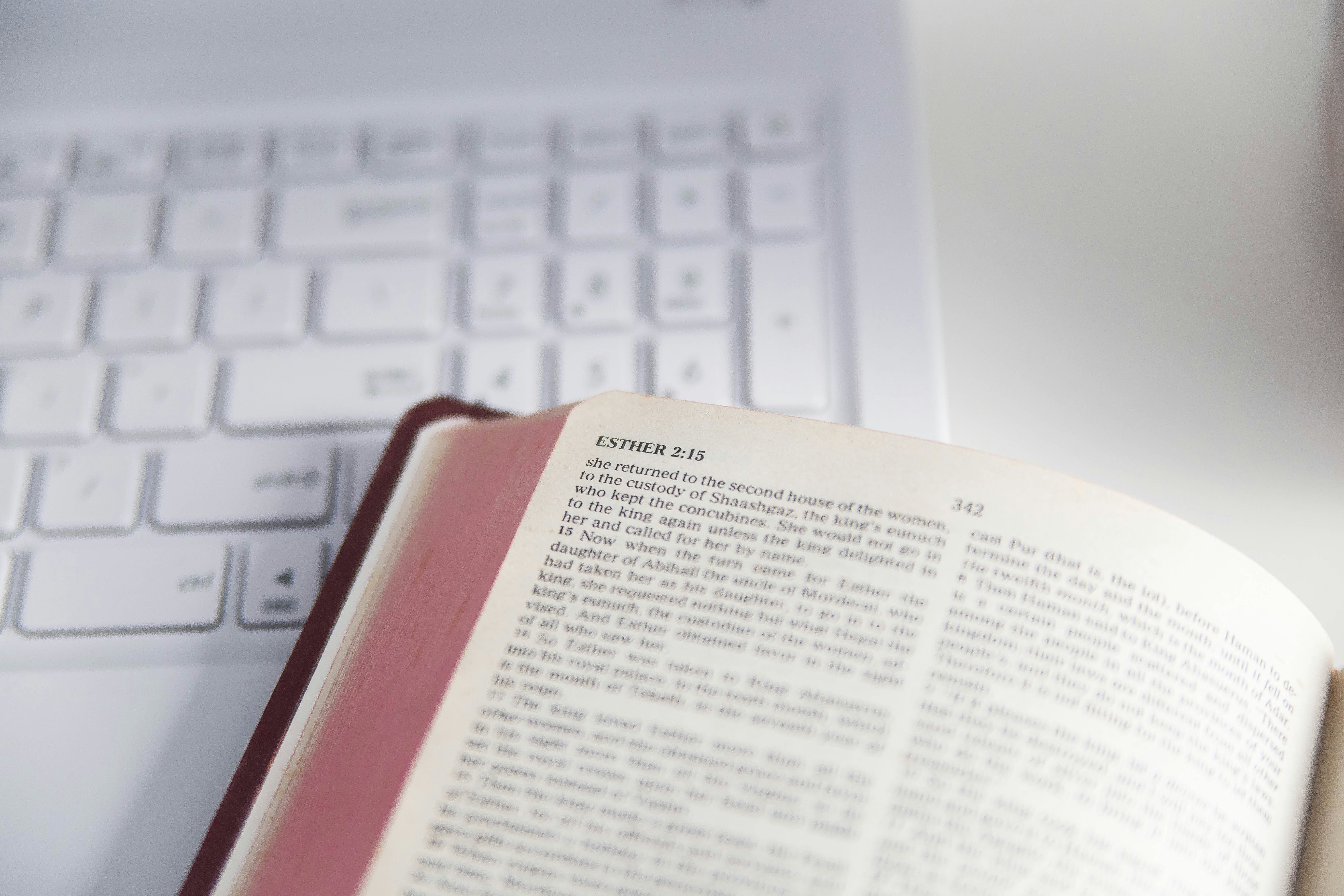 Open book rests near a white laptop keyboard