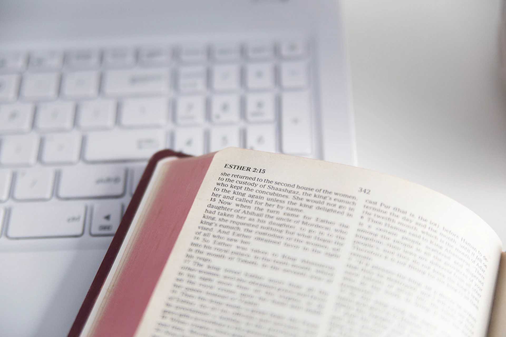 Open book rests near a white laptop keyboard