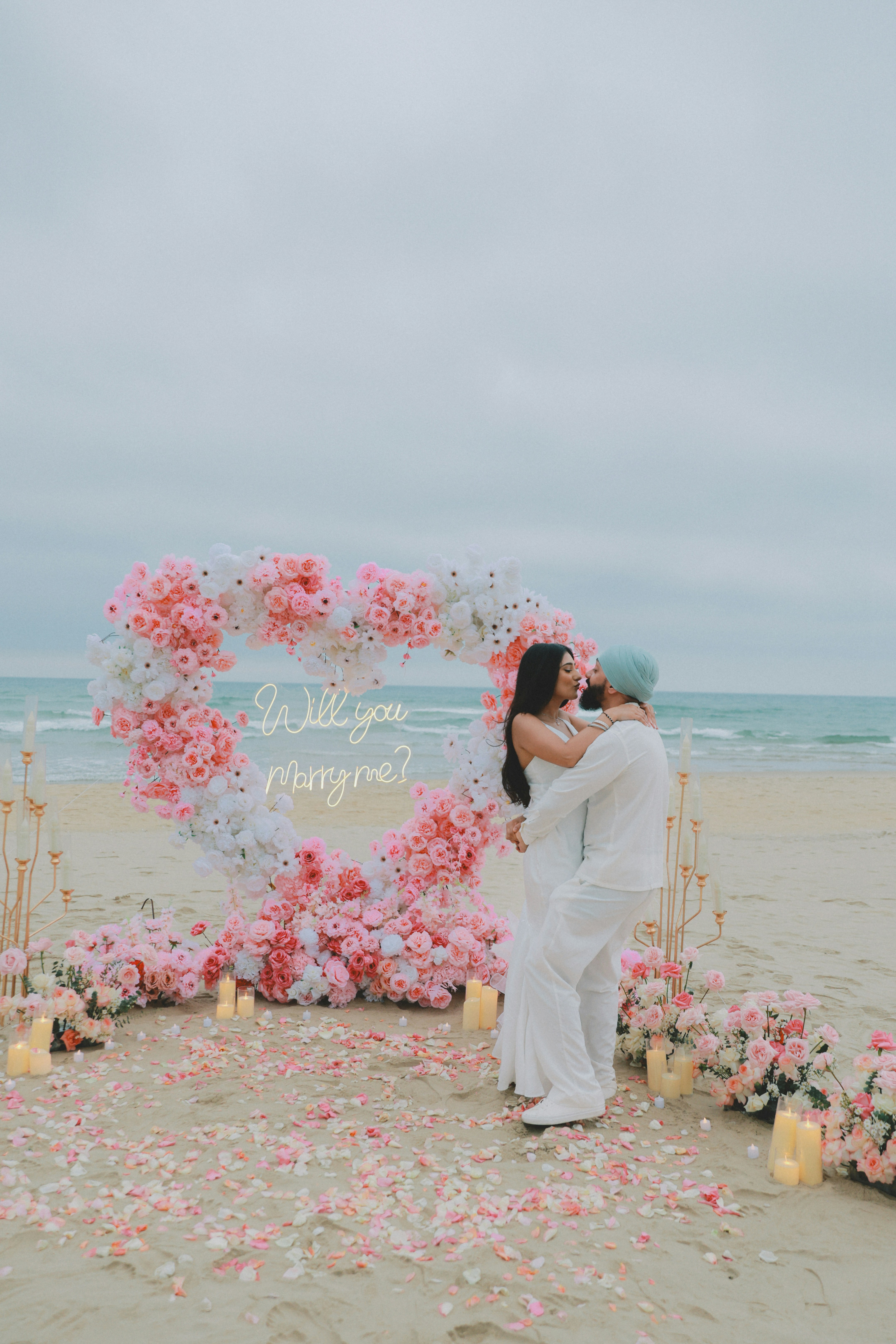 Couple s’embrassant sur la plage avec une proposition en cœur fleuri