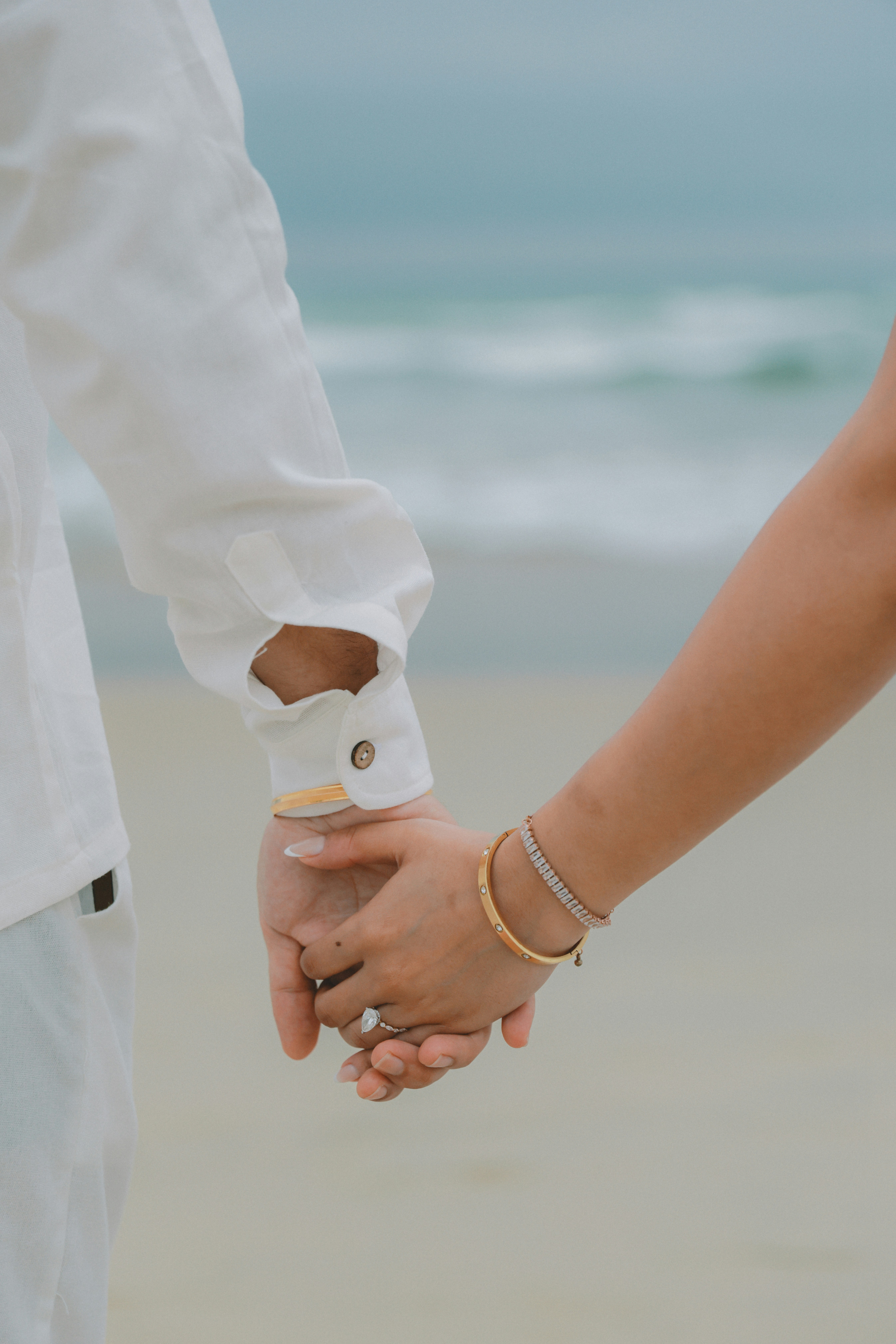 Un couple se tenant la main sur une plage de sable.