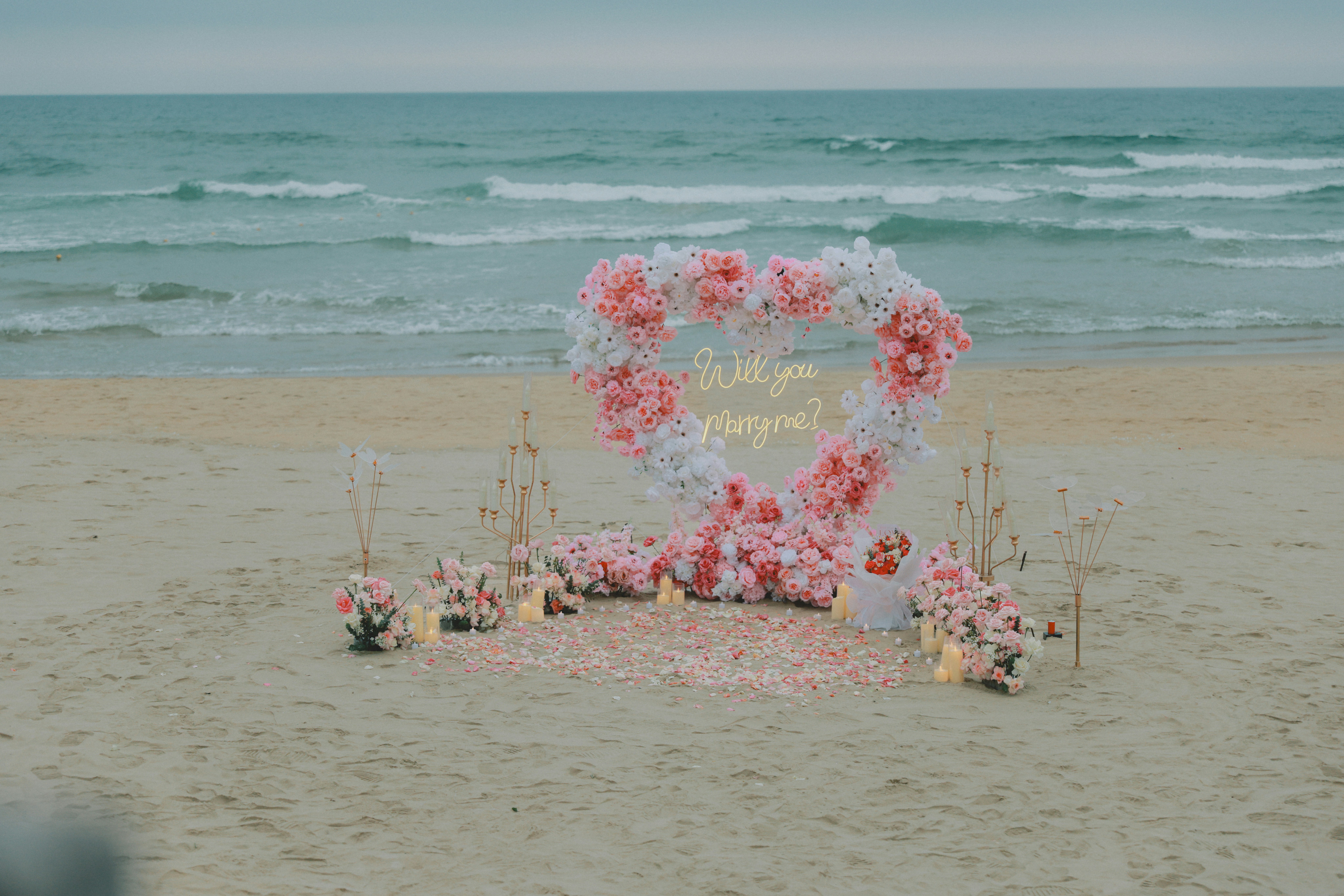 Proposition d’arche florale en forme de cœur sur une plage de sable