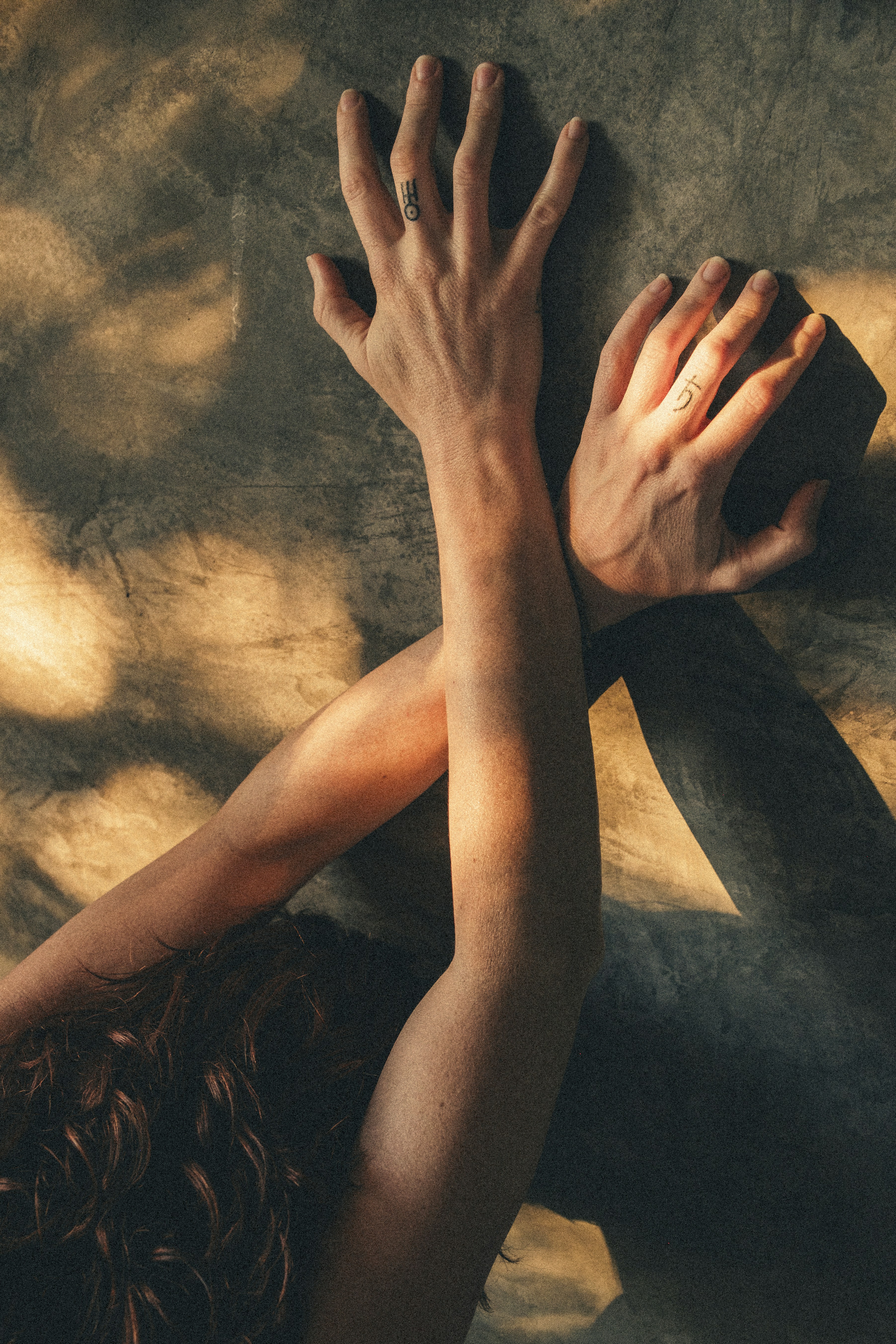 Les bras de la femme croisés contre un mur texturé d’ombres