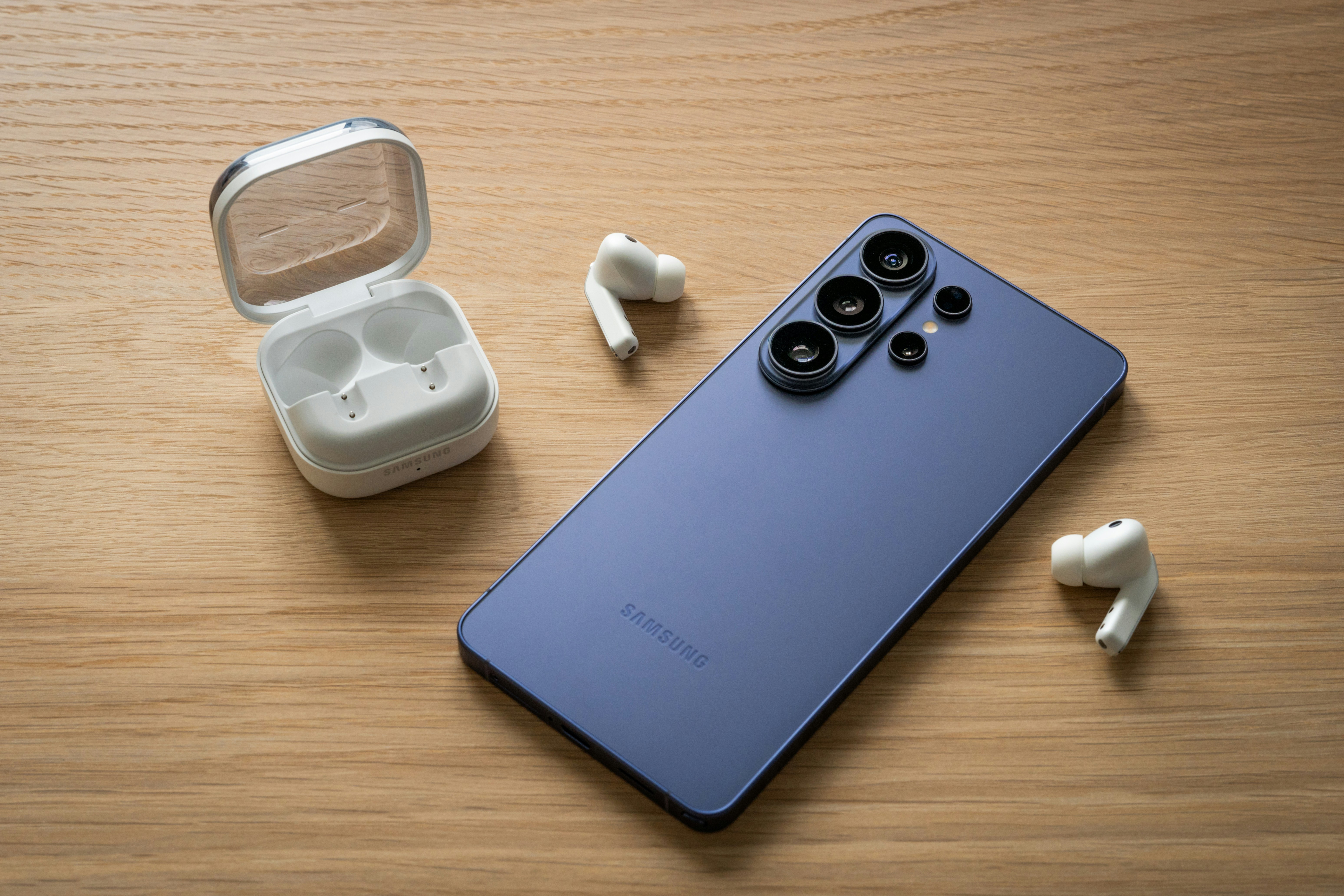 Smartphone with wireless earbuds and charging case on wood