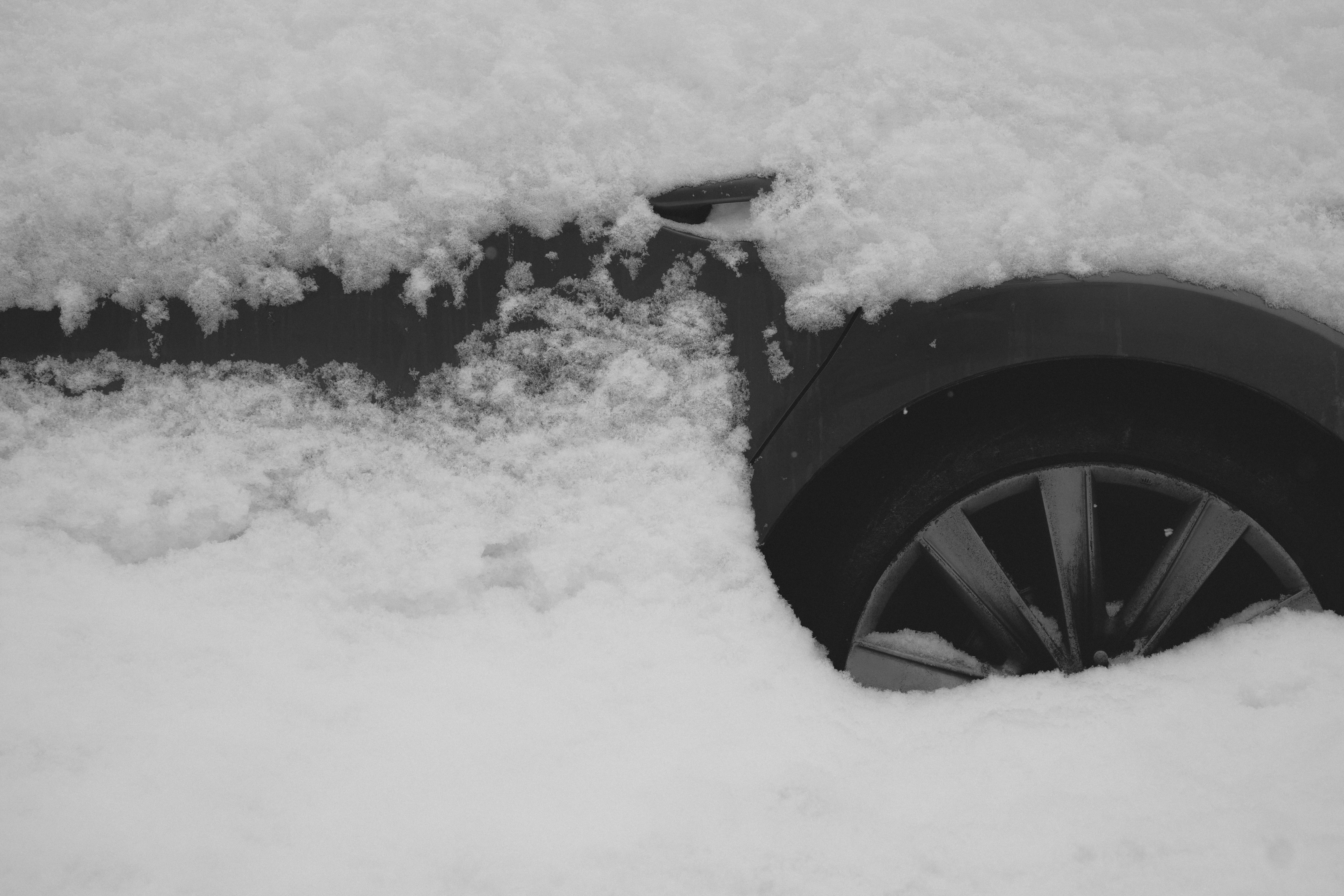 A car door and wheel covered in snow.
