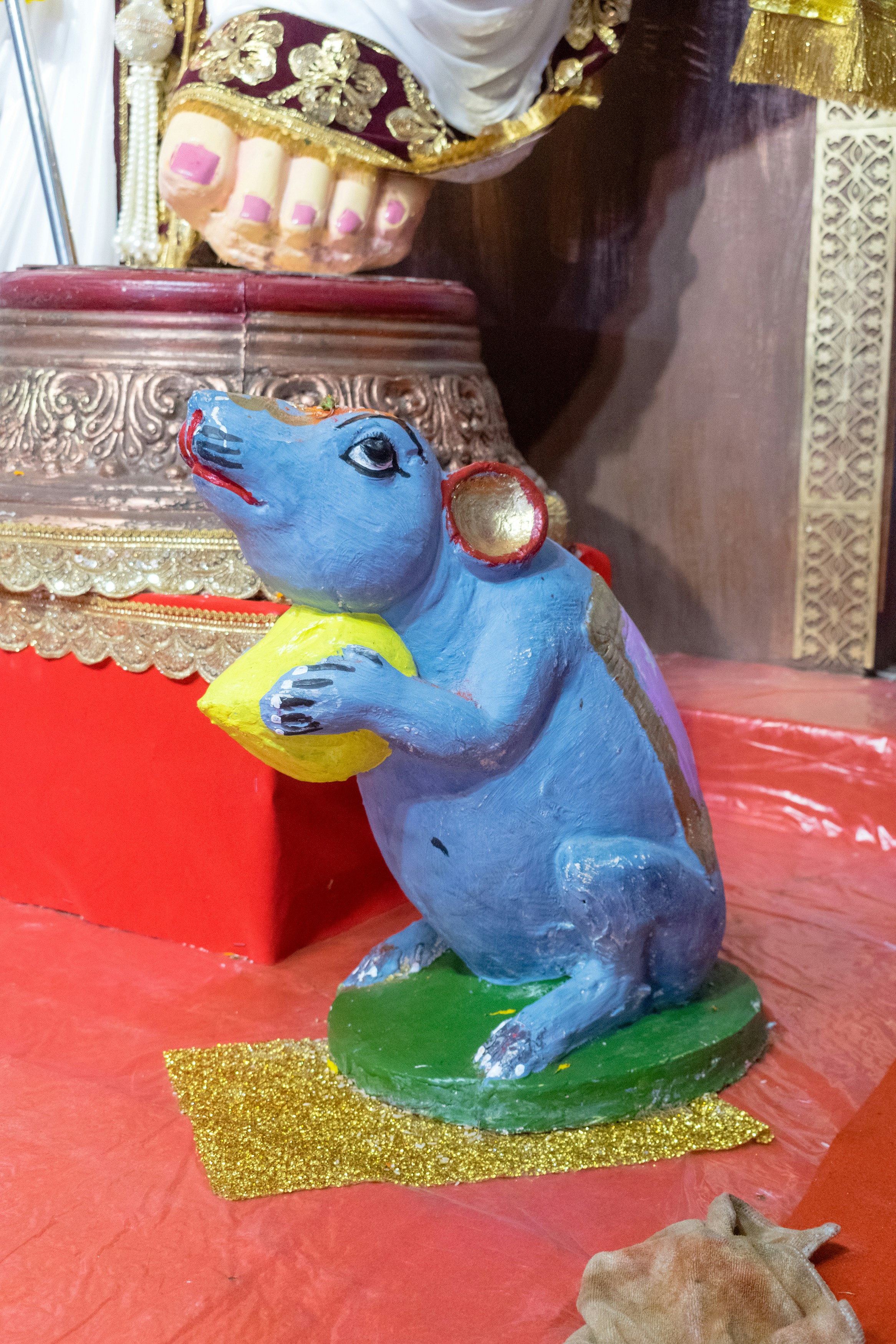 Uma estátua de rato azul segurando um objeto amarelo