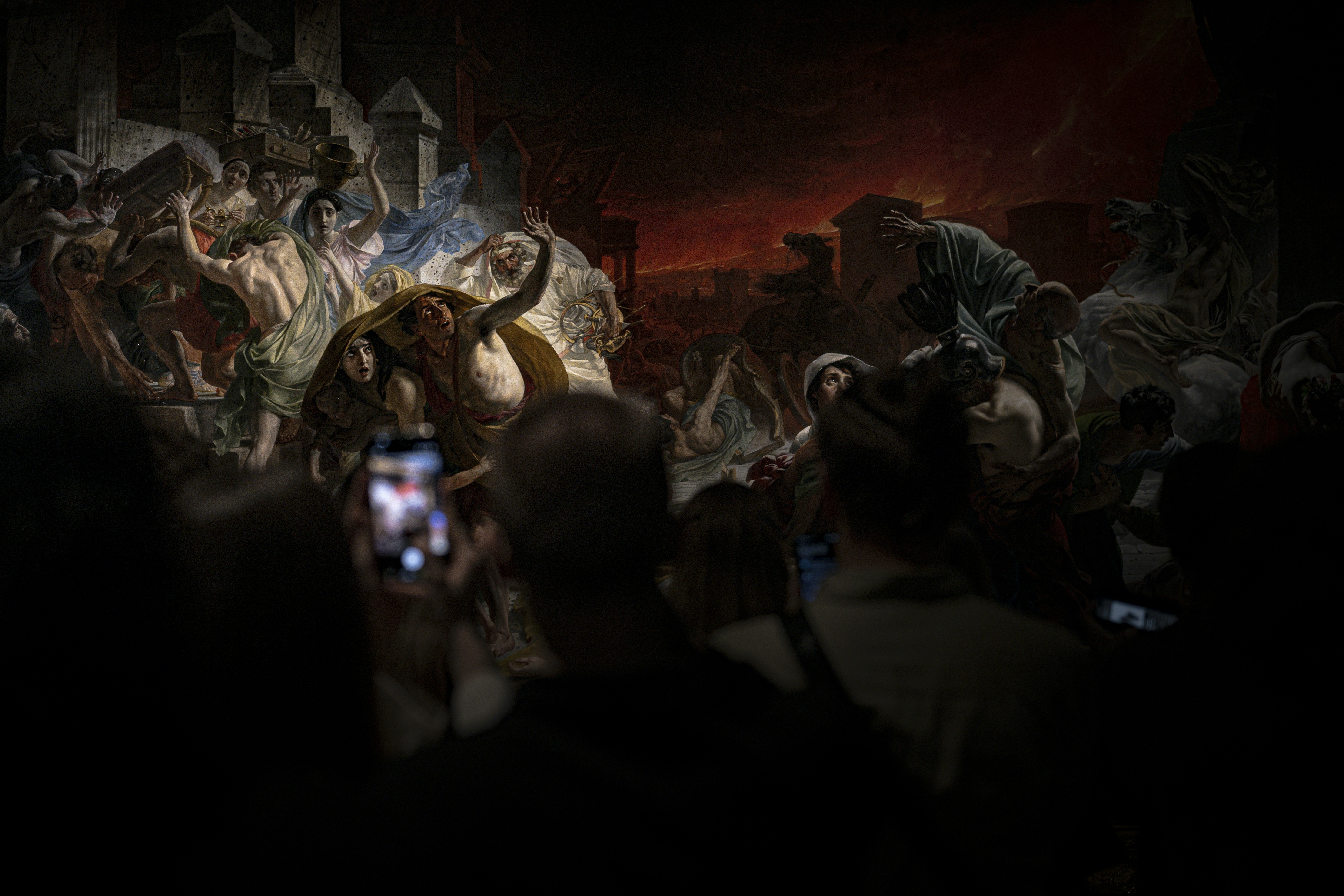 People filming a large painting of a chaotic scene