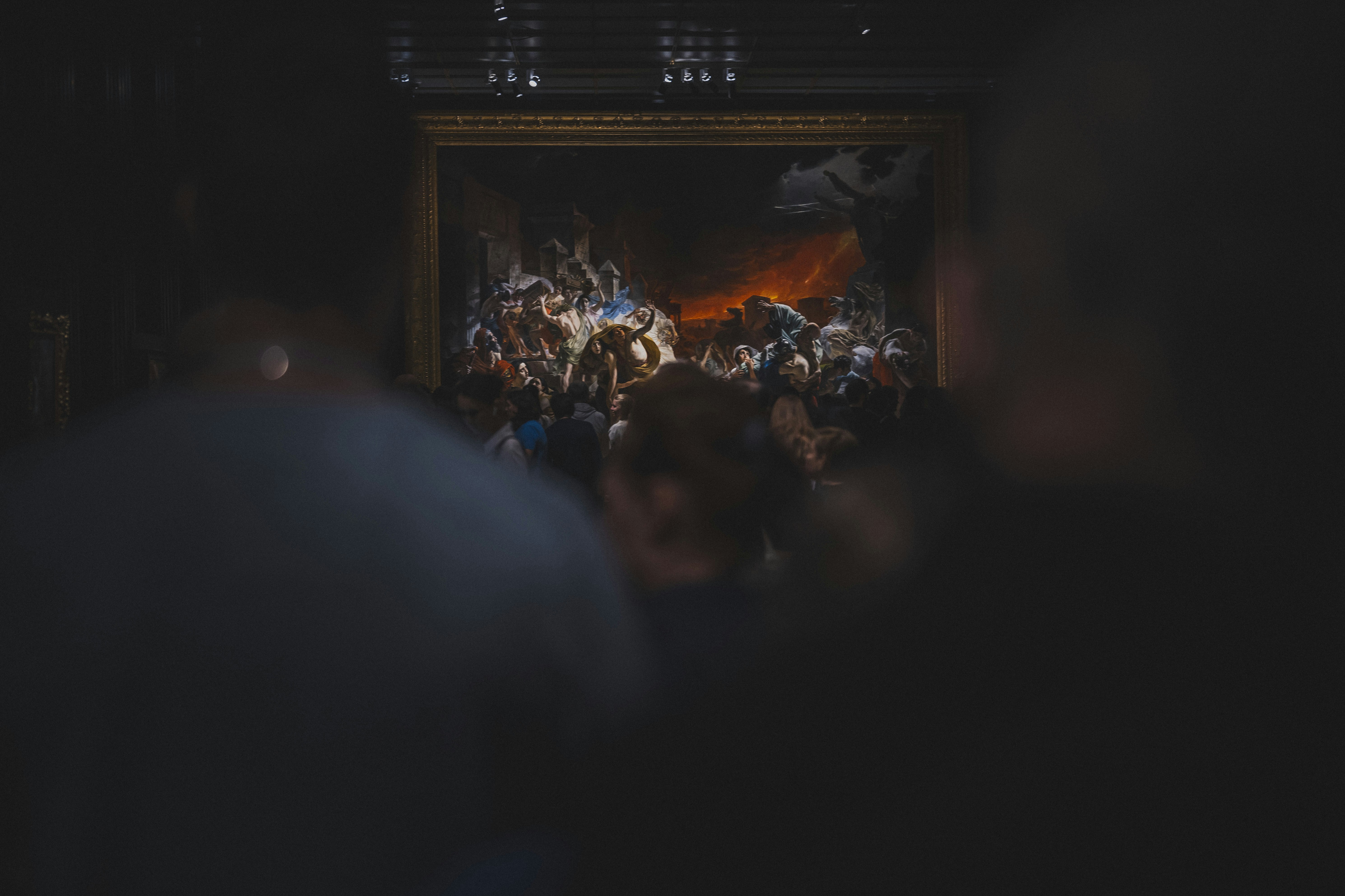 People viewing a painting in a dimly lit gallery