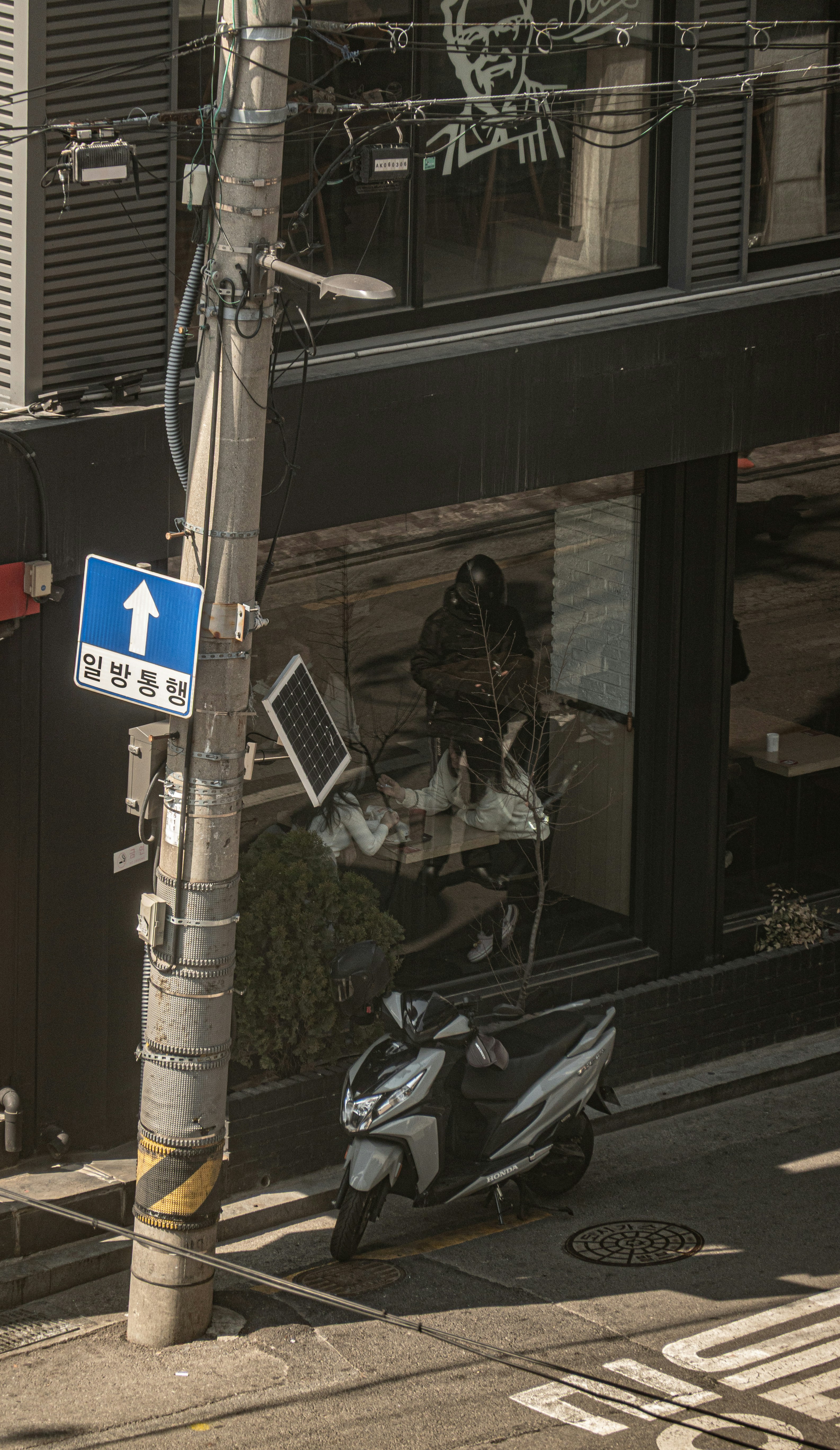 A scooter parked on a sidewalk near a pole.