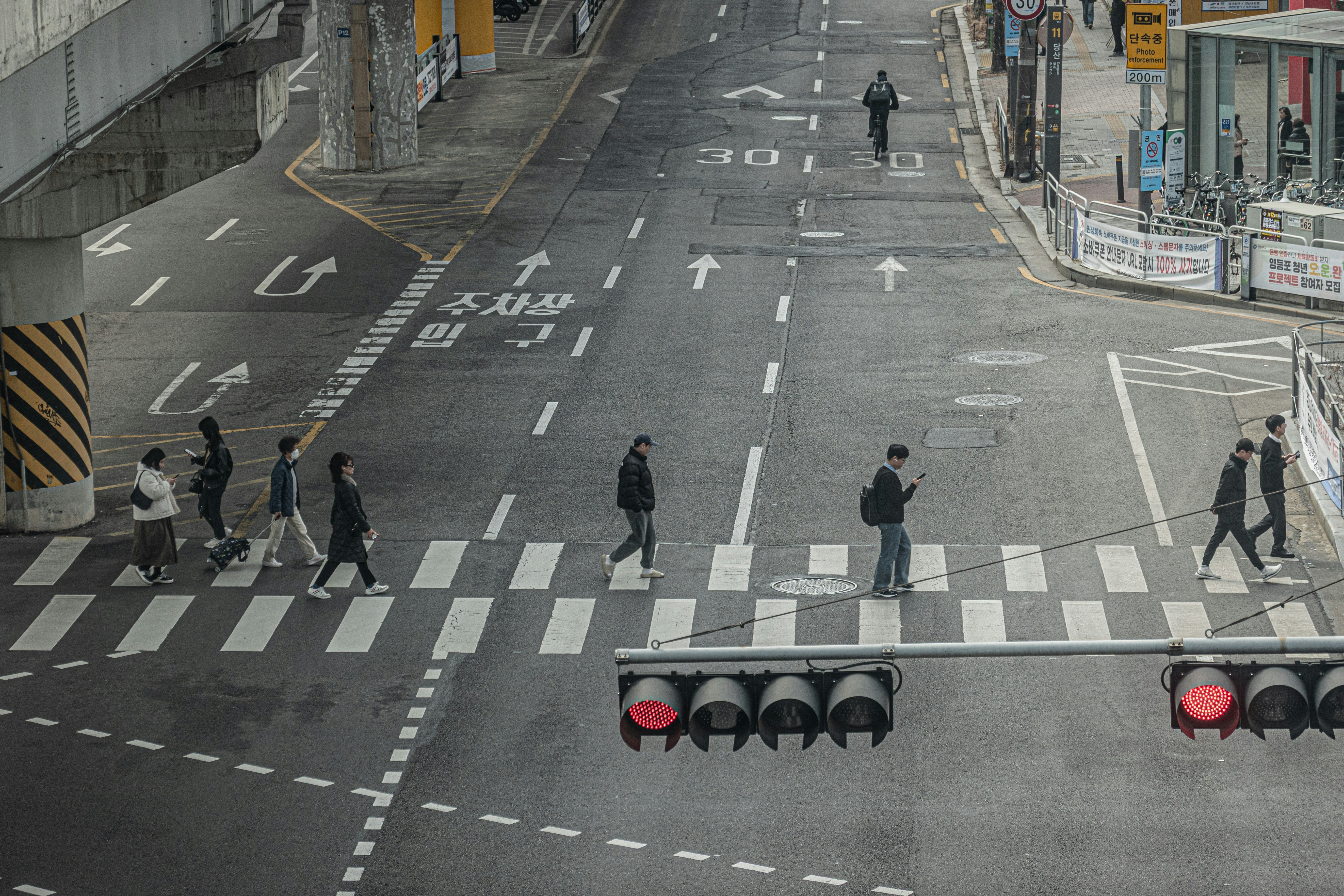People crossing a street at a crosswalk with traffic lights.