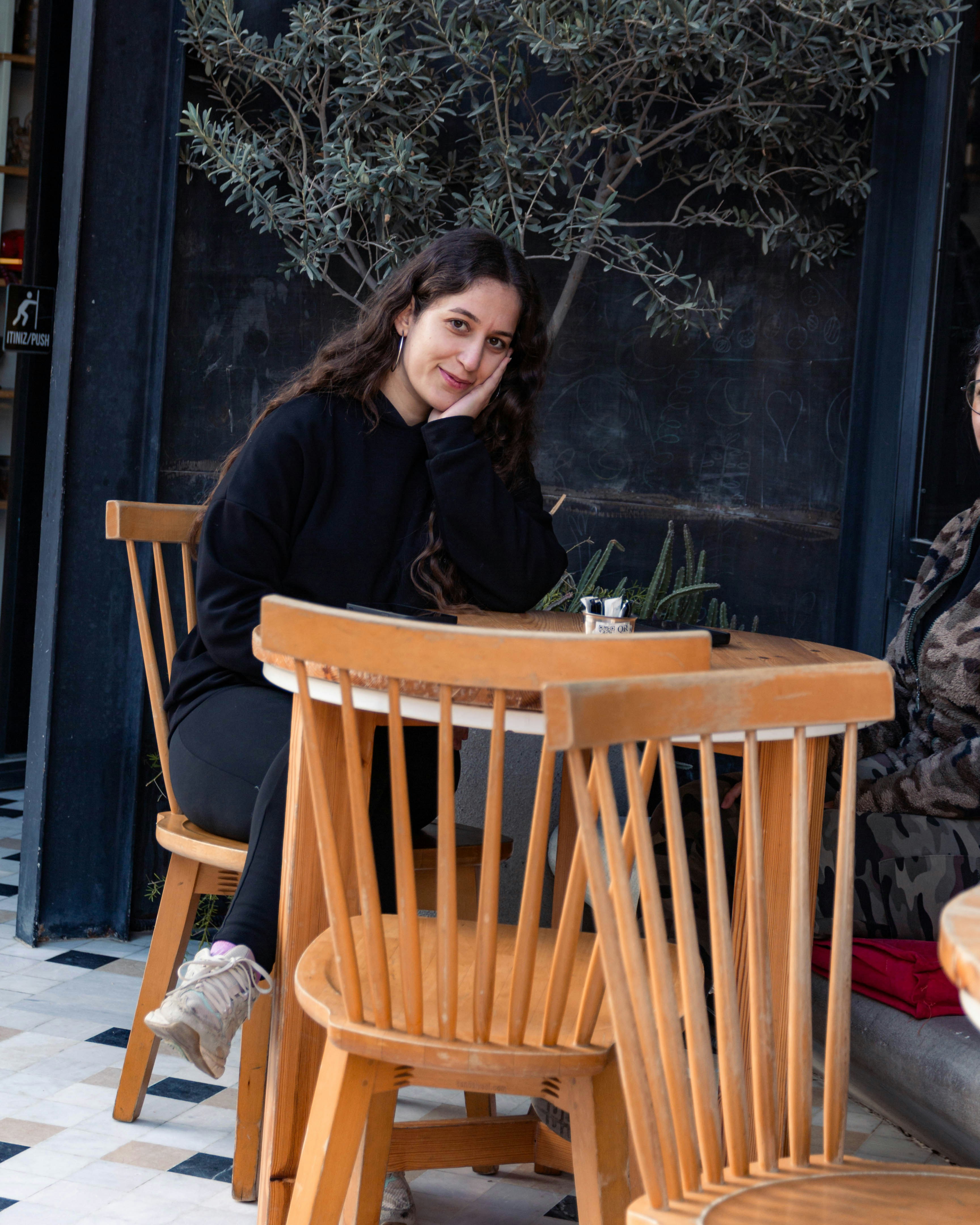 Young woman sitting at a wooden table outdoors