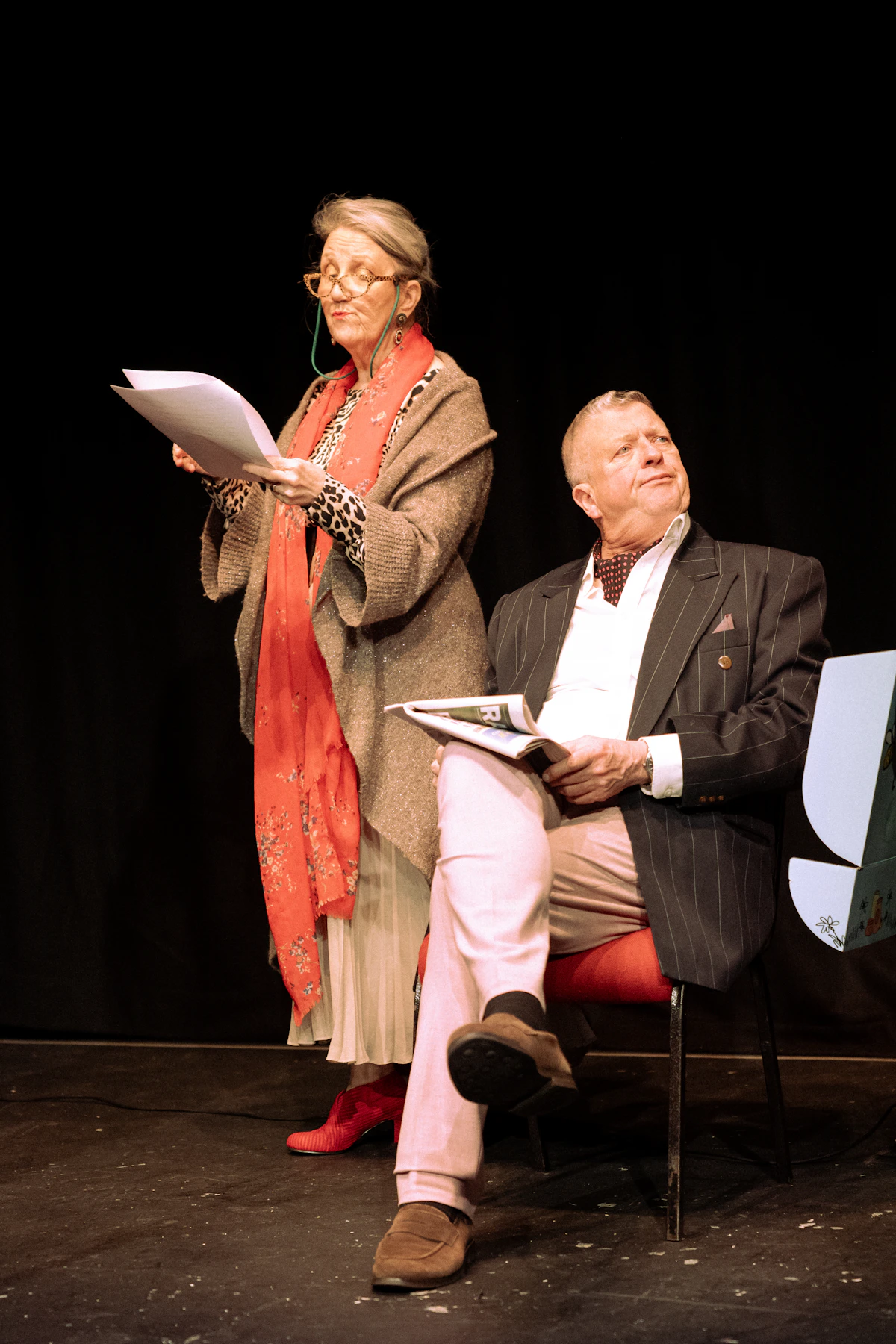 Two actors rehearsing a scene on stage with scripts