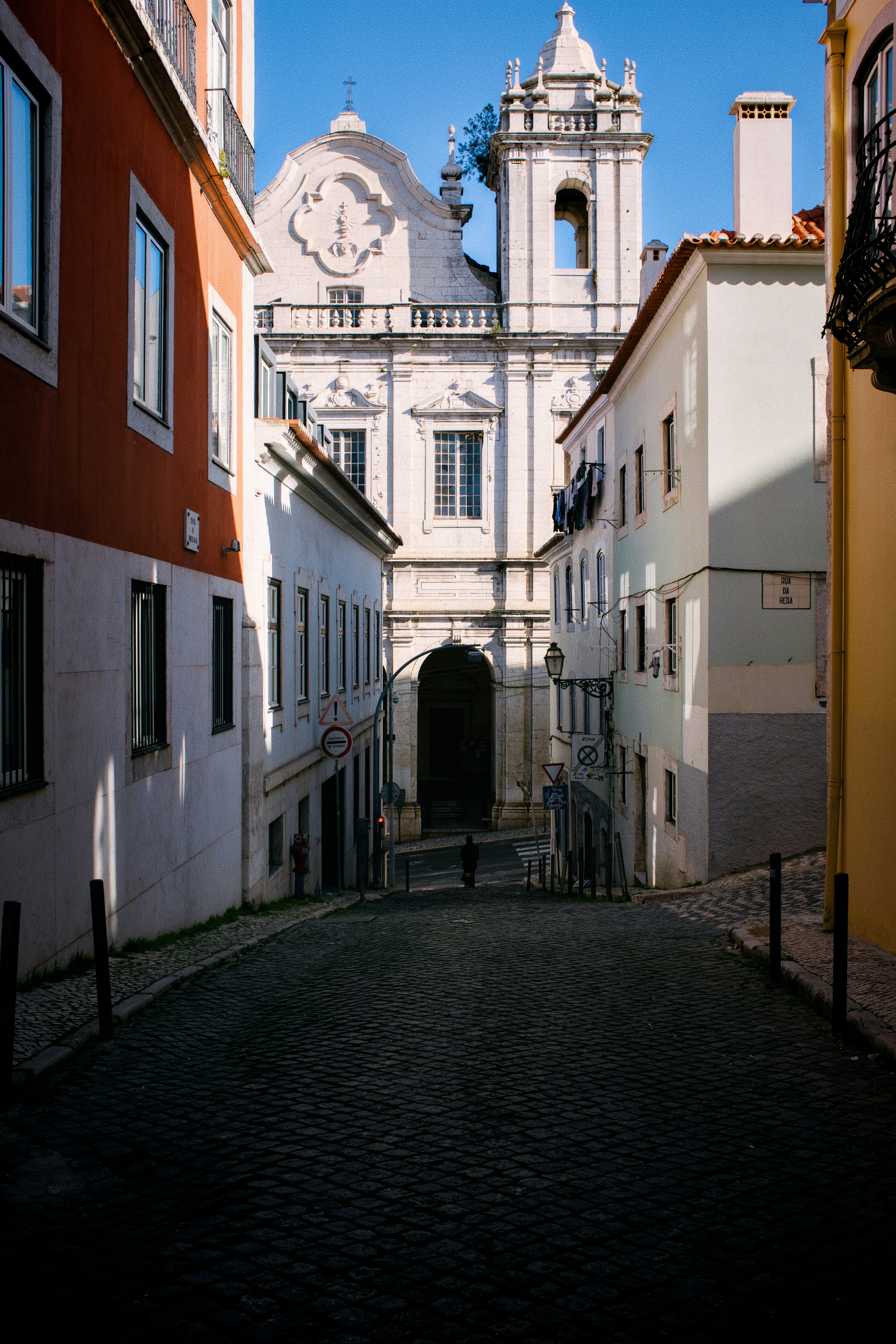 Cobblestone street leads to a white church building.